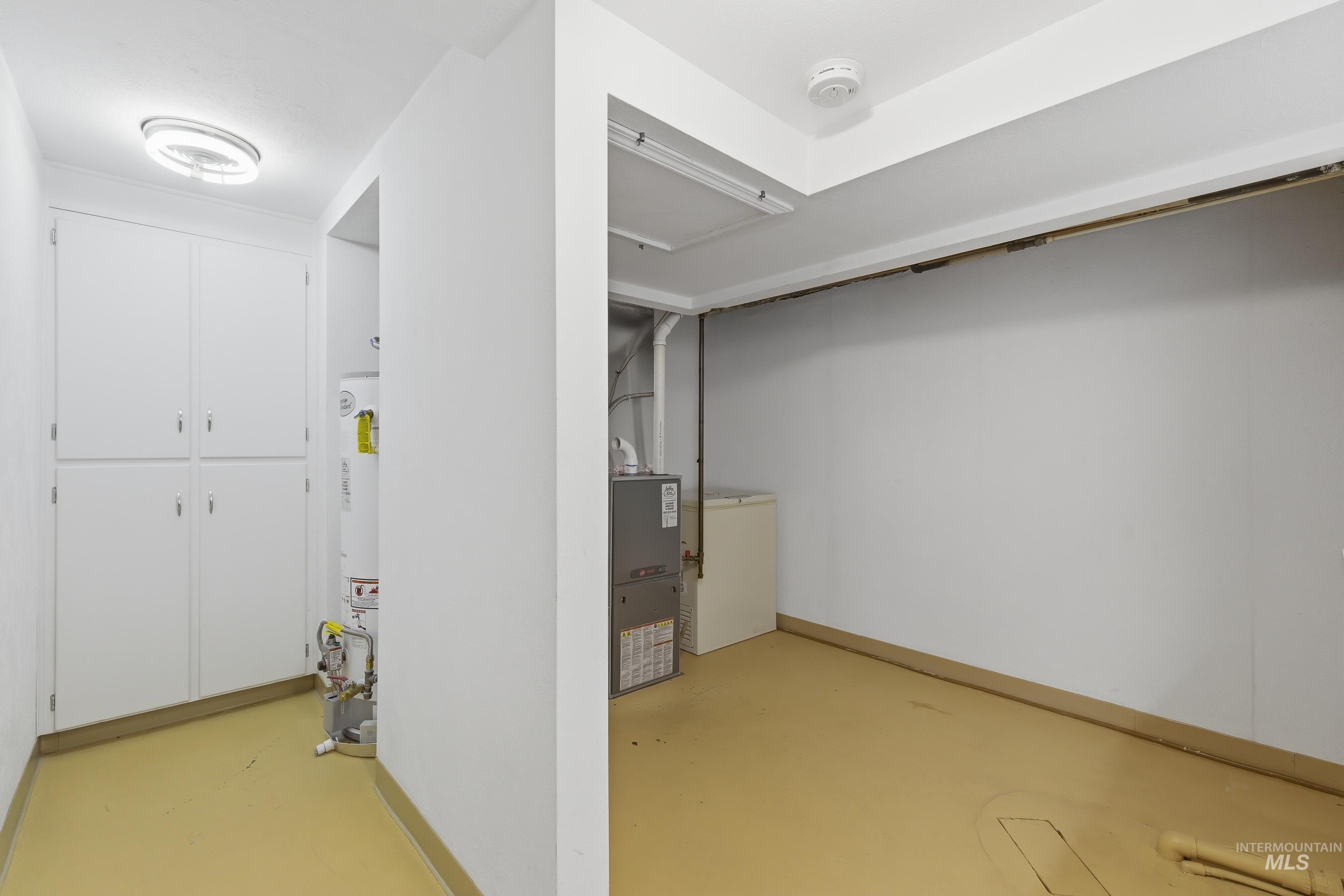 Utility area with built-in cabinetry, a water heater, and a furnace unit