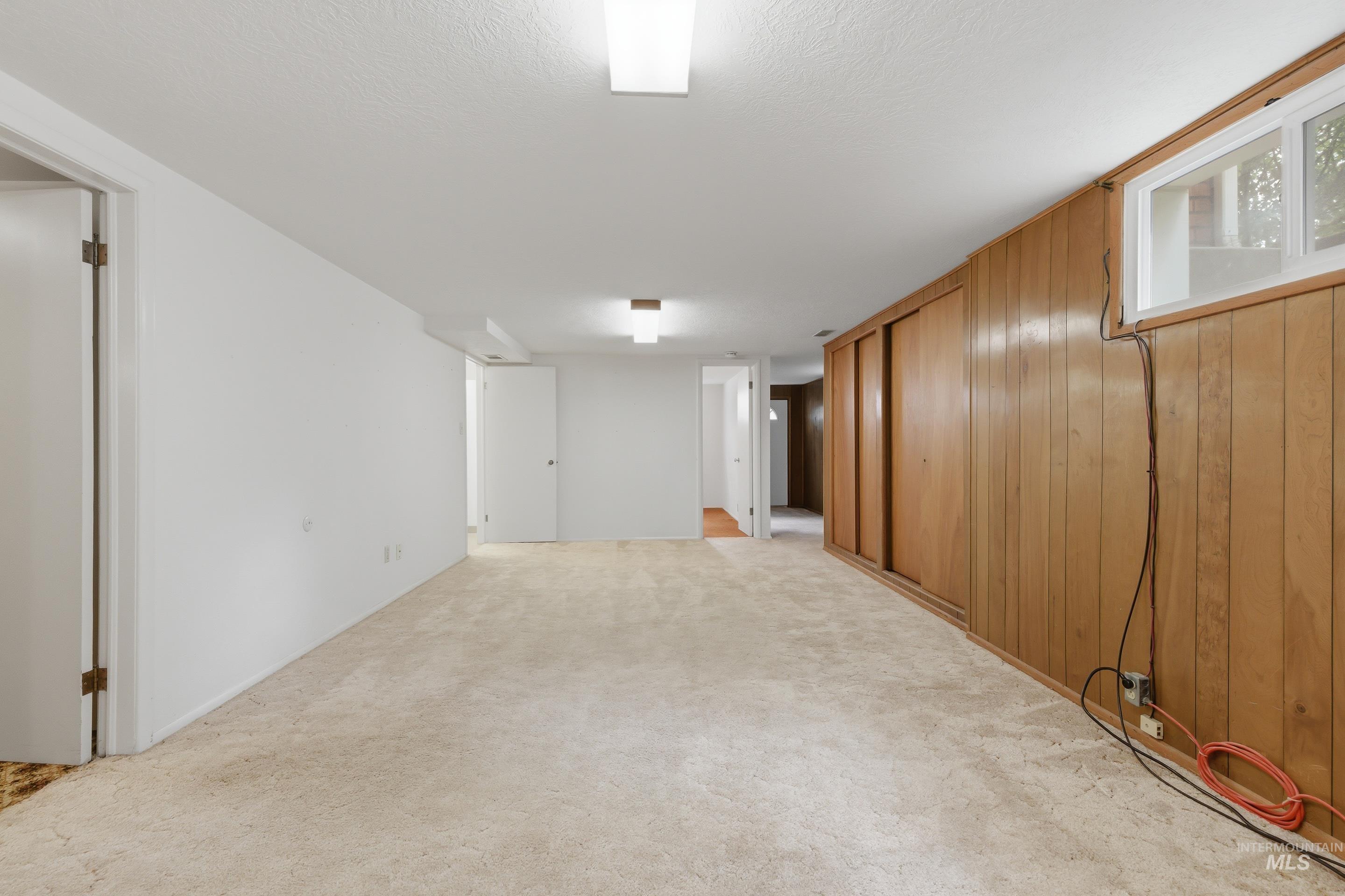Carpeted room featuring a white painted wall and wood paneling