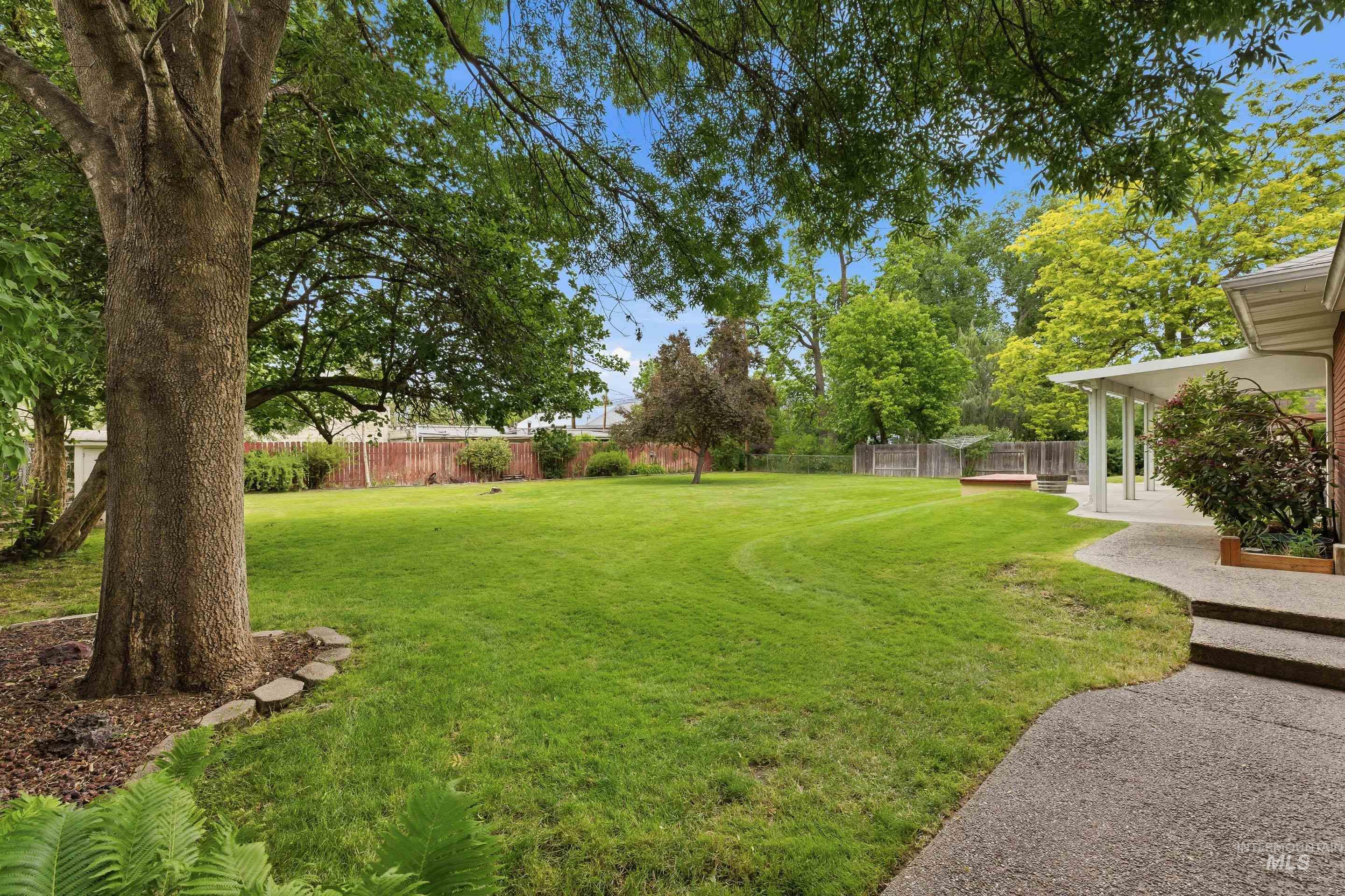 Expansive private yard featuring mature trees and a manicured lawn