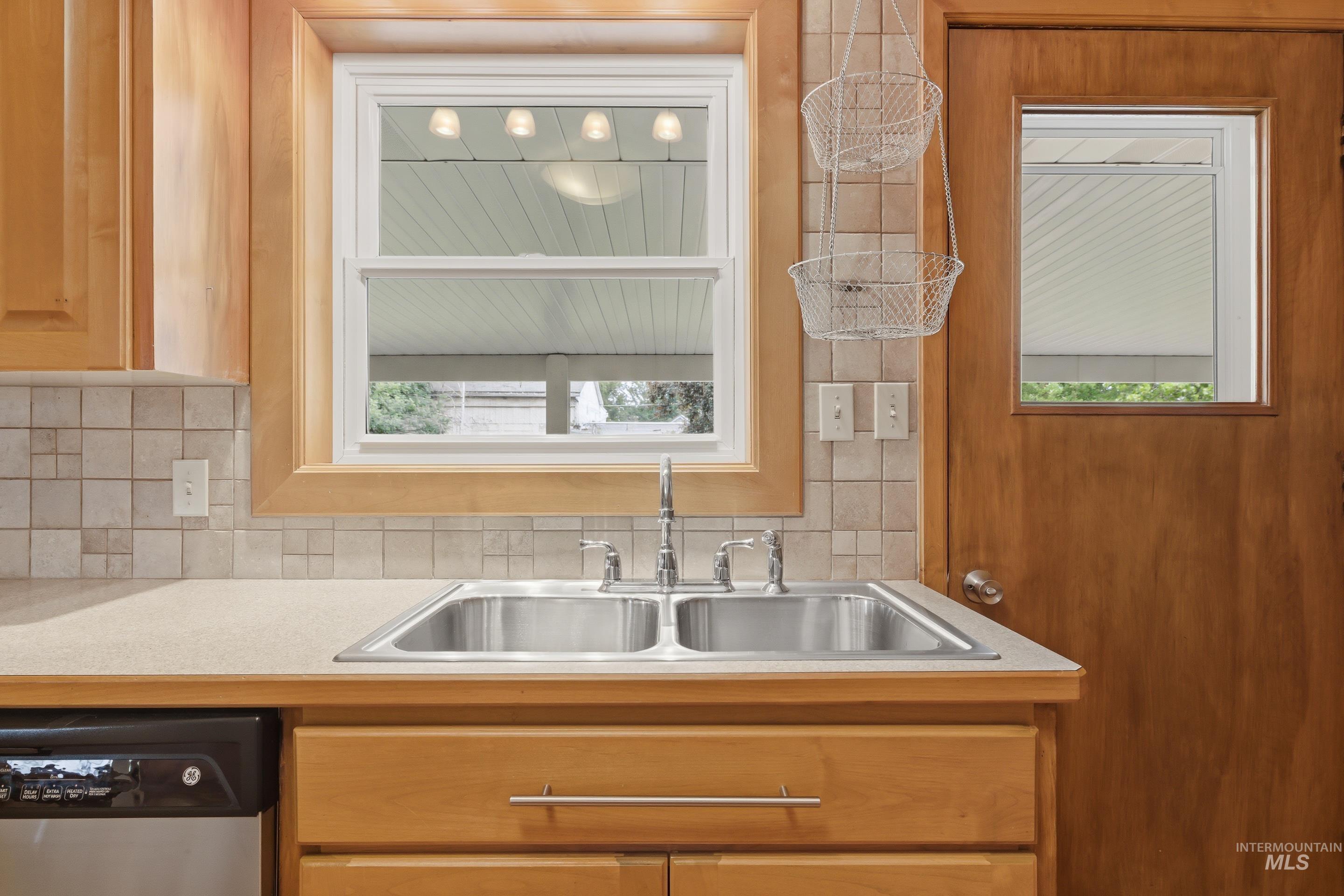 Stainless steel double basin kitchen sink with chrome faucet, set into a light-toned countertop