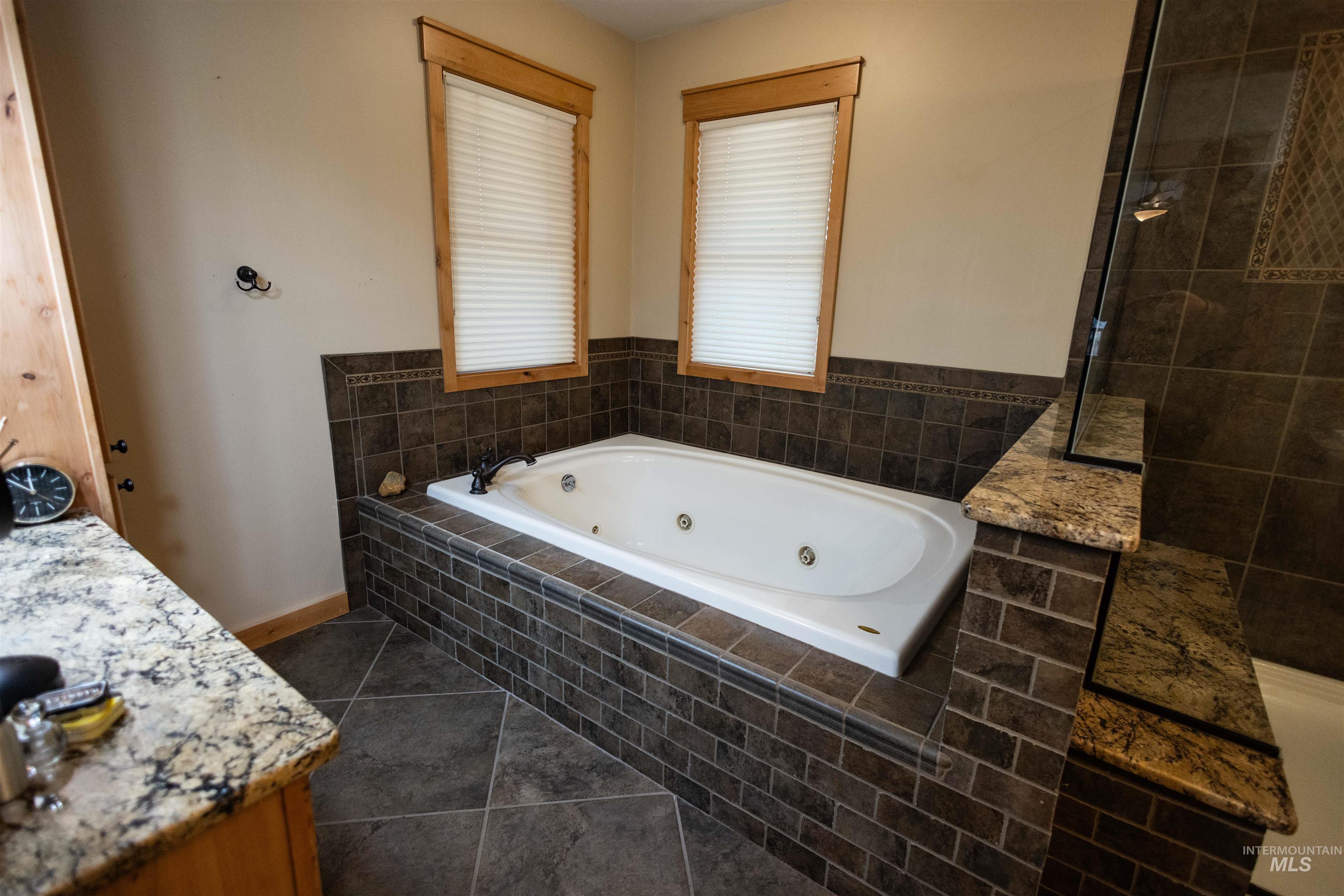 Full bath featuring a whirlpool tub, dark tile patterned floors, and vanity