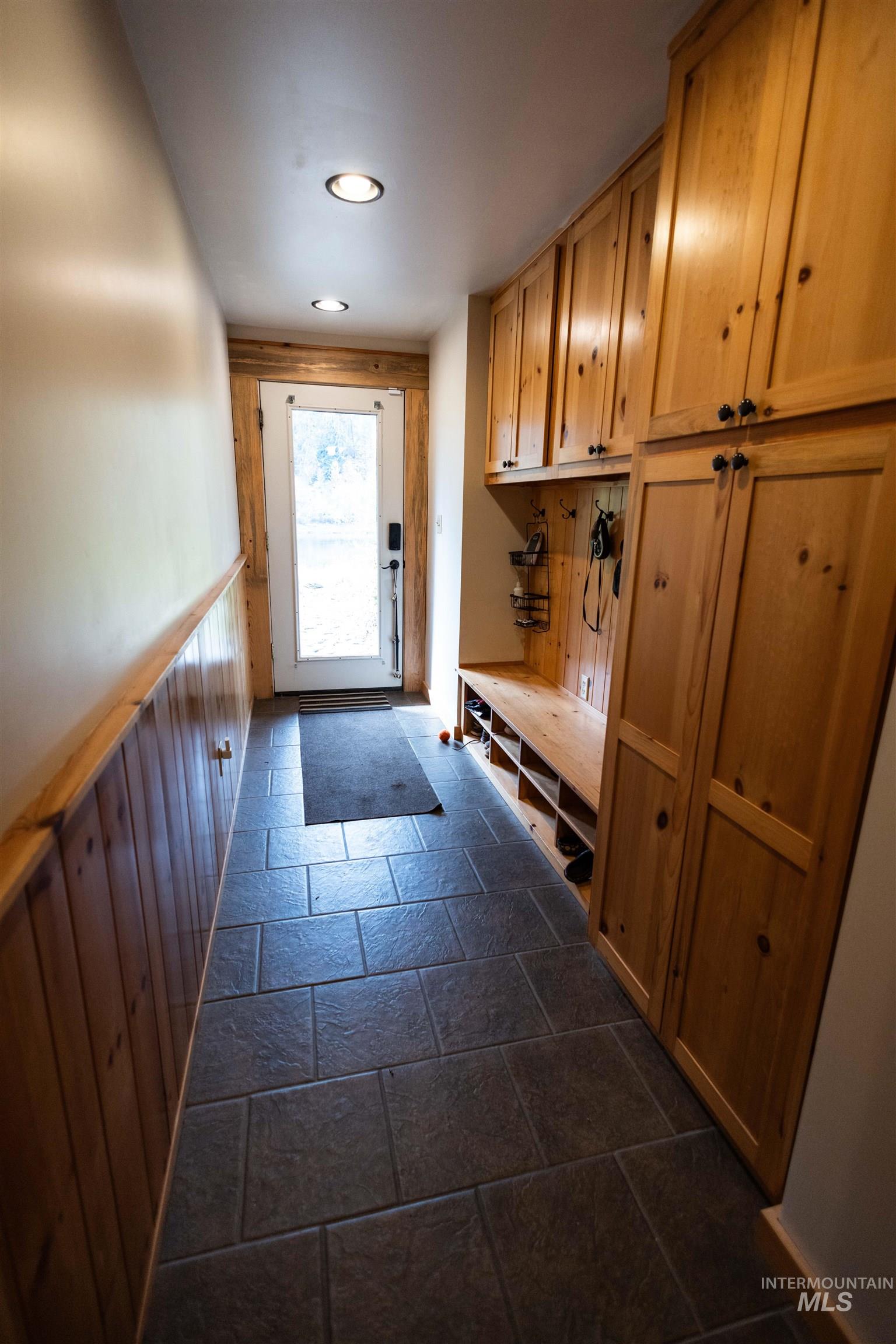 Mudroom featuring stone tile flooring, wood walls, a wainscoted wall, and recessed lighting