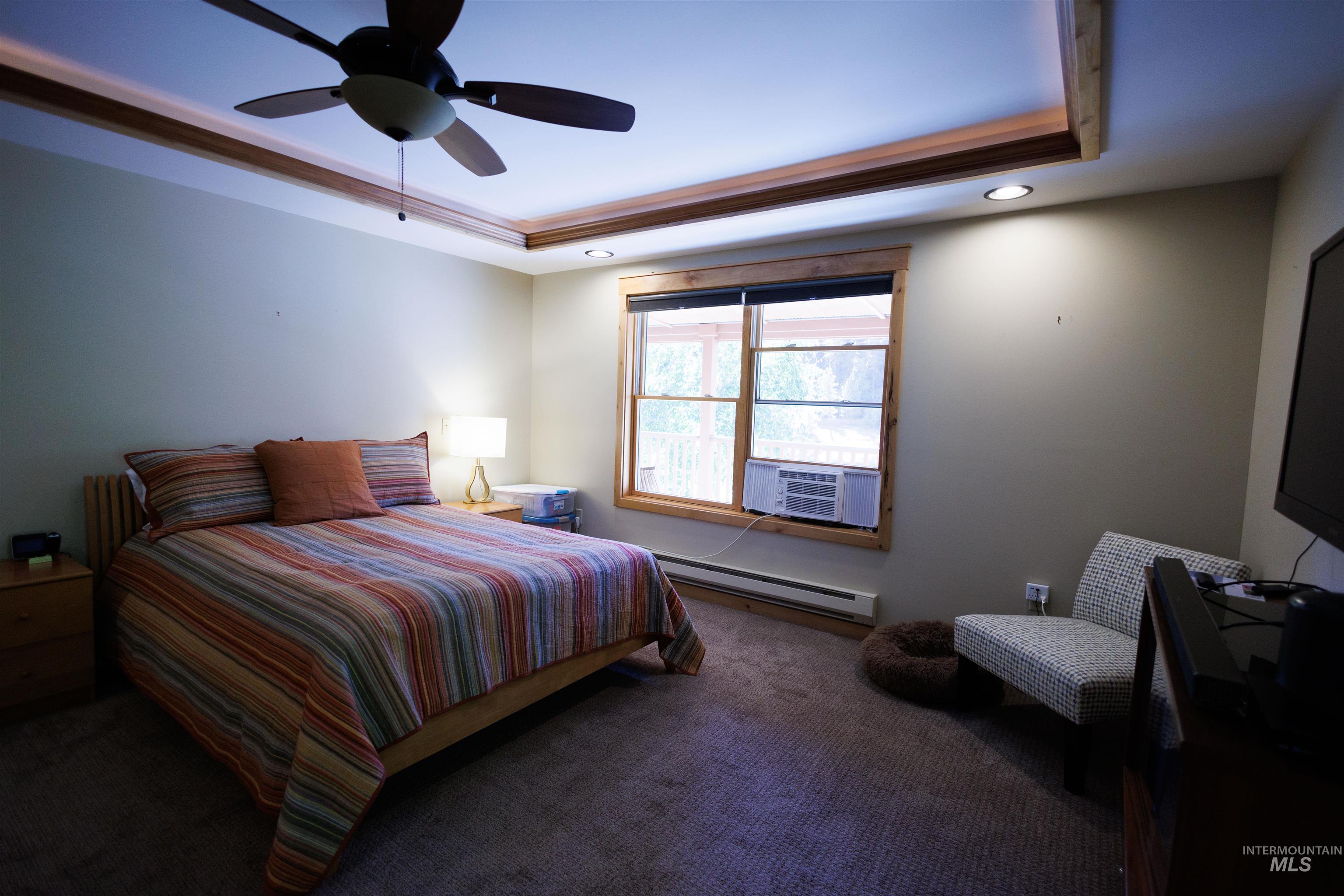 Bedroom featuring a raised ceiling, carpet flooring, a baseboard radiator, ceiling fan, and recessed lighting