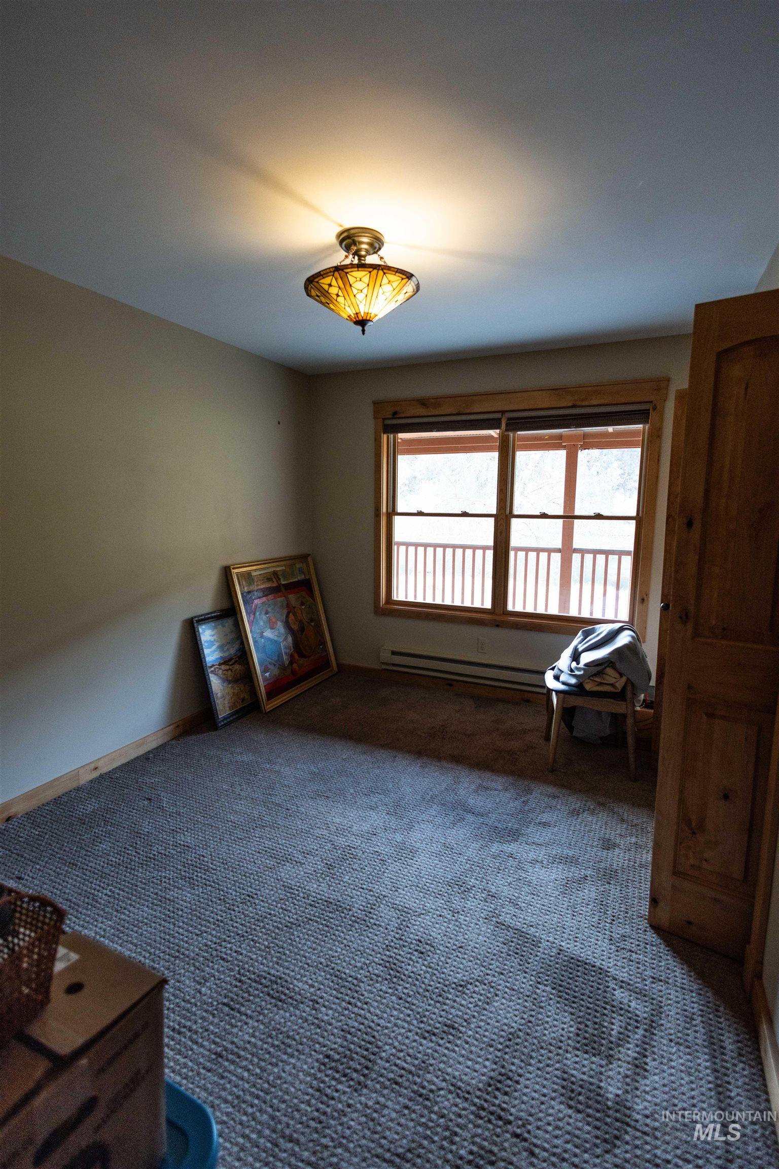 Unfurnished living room featuring carpet and a baseboard radiator