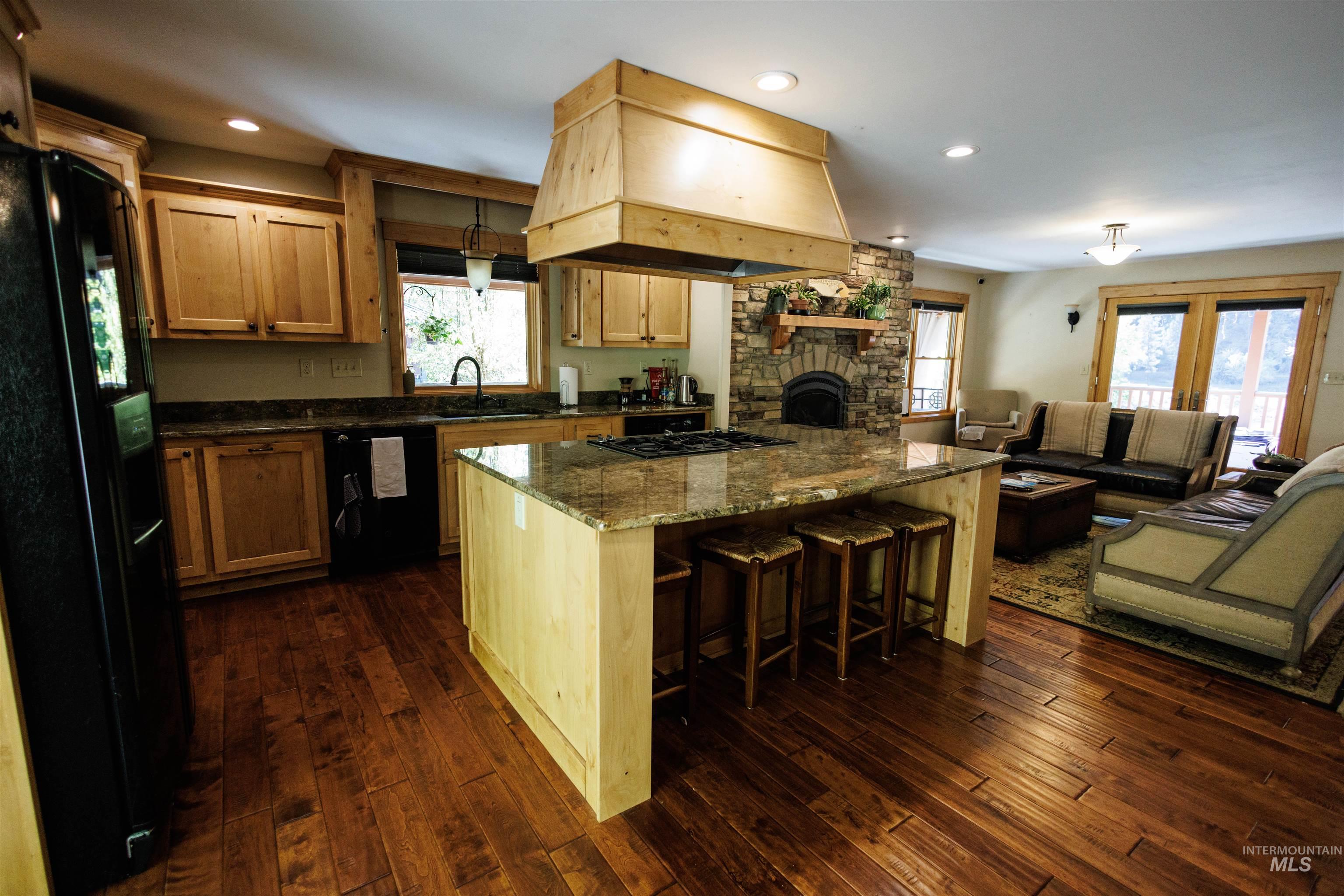 Kitchen with black appliances, premium range hood, dark wood-style floors, open floor plan, and recessed lighting