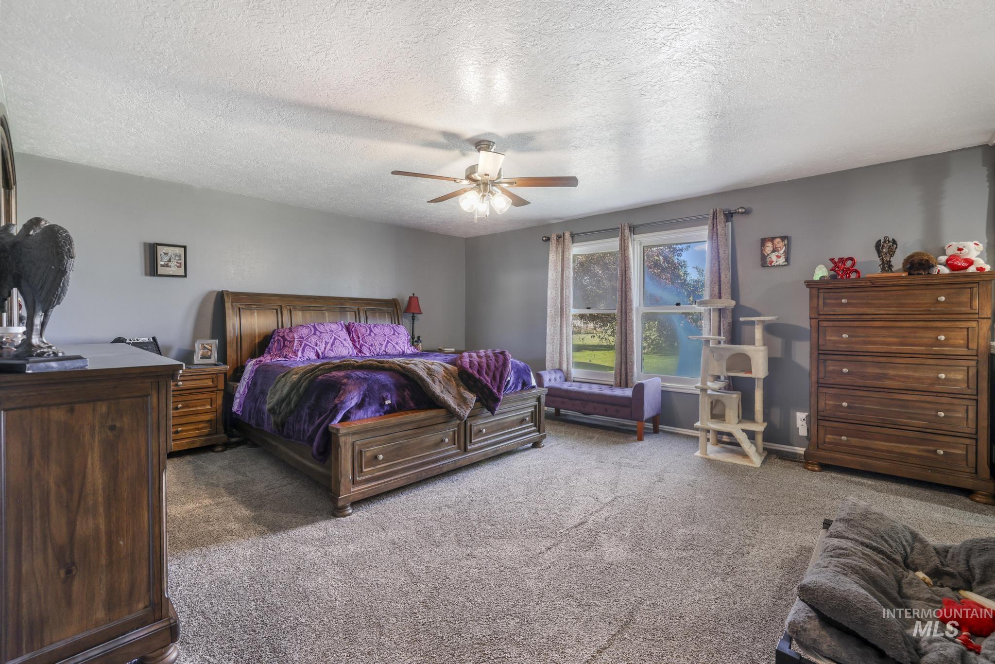 Carpeted bedroom featuring a textured ceiling and ceiling fan