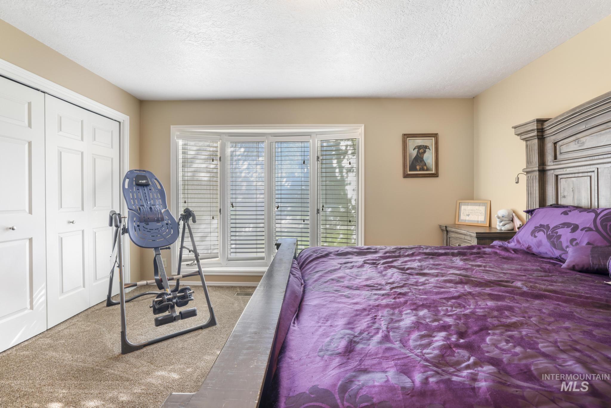 Carpeted bedroom featuring a textured ceiling and a closet