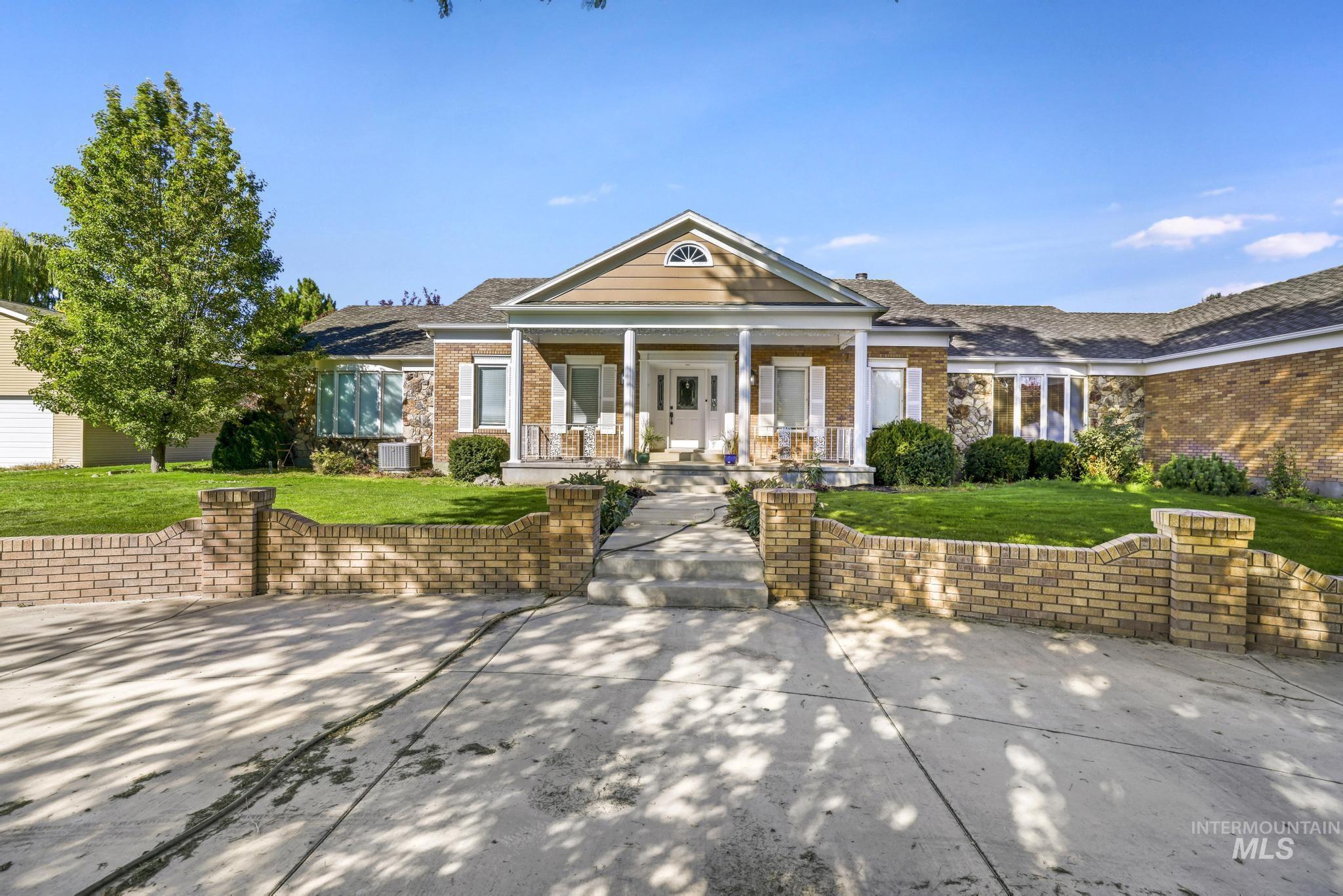 View of front facade with covered porch, brick siding, and a front yard