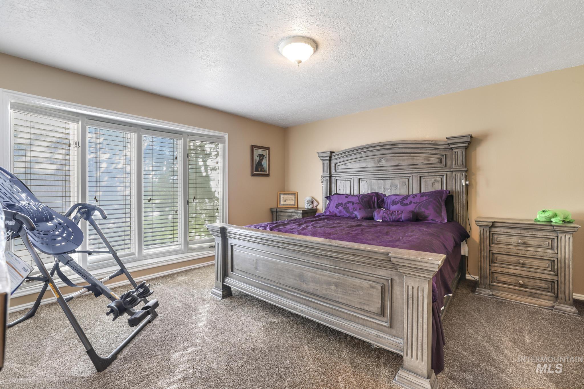 Carpeted bedroom featuring a textured ceiling and baseboards