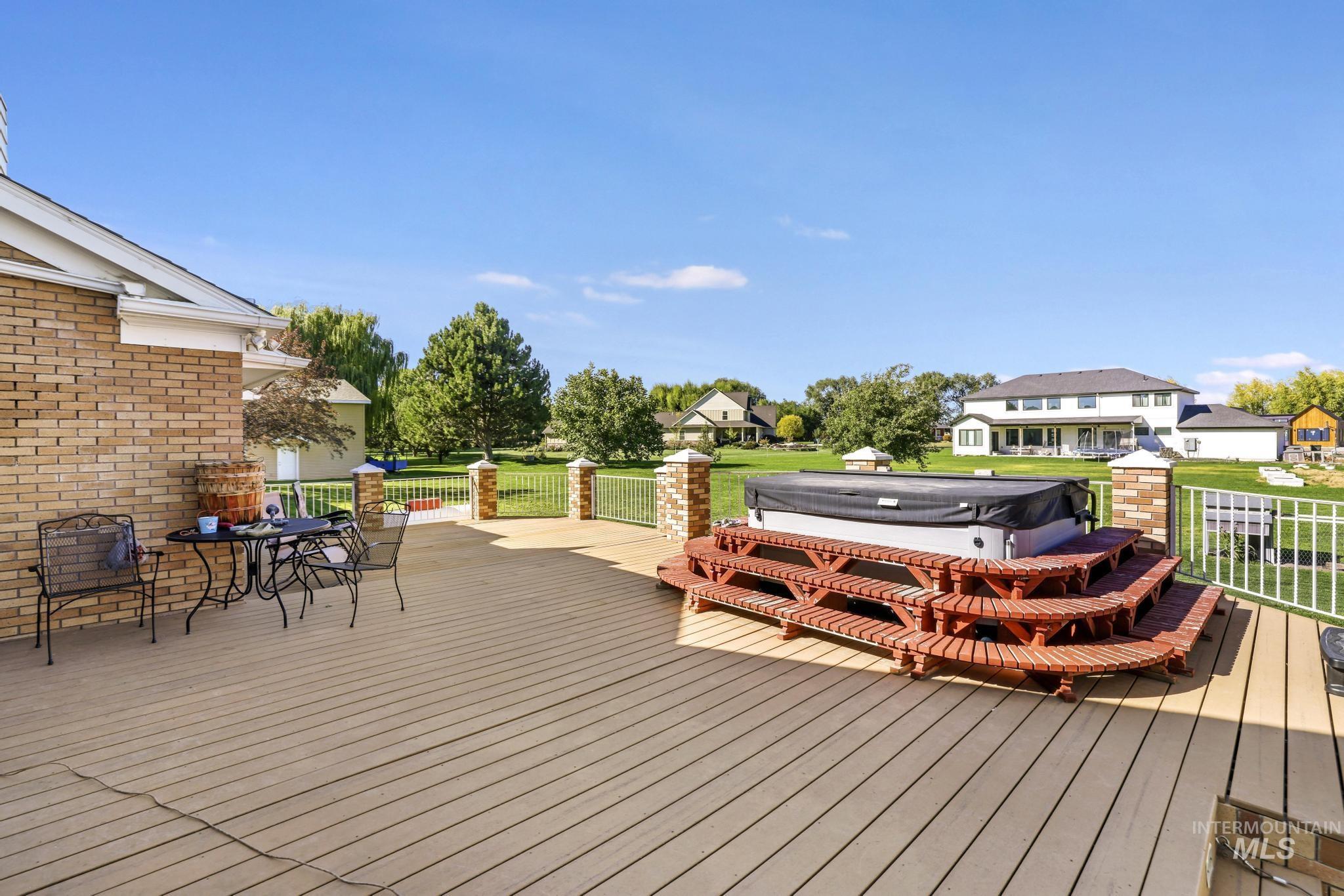Wooden terrace featuring outdoor dining space, a residential view, a covered hot tub, and a yard