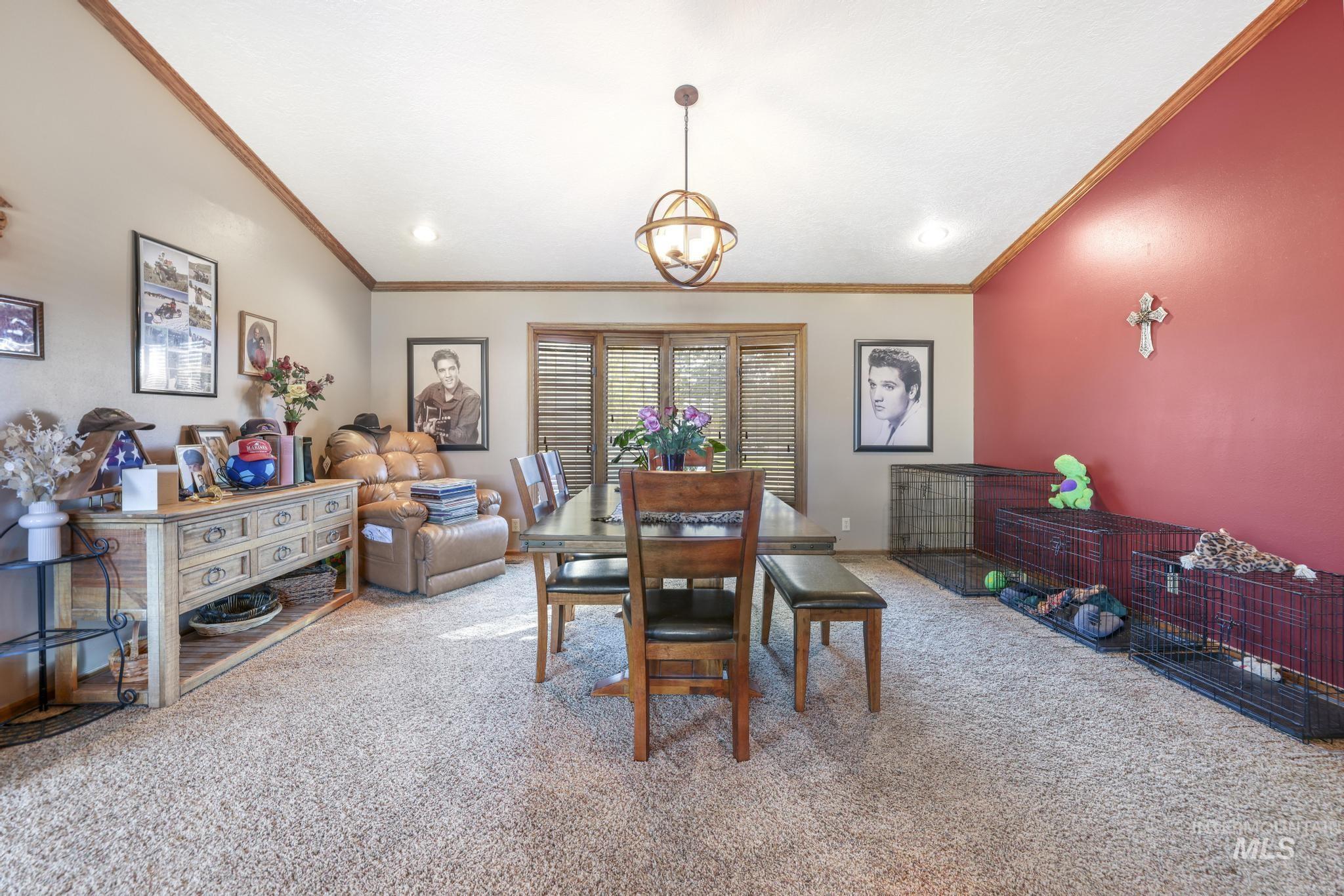 Dining space with light colored carpet, ornamental molding, and lofted ceiling