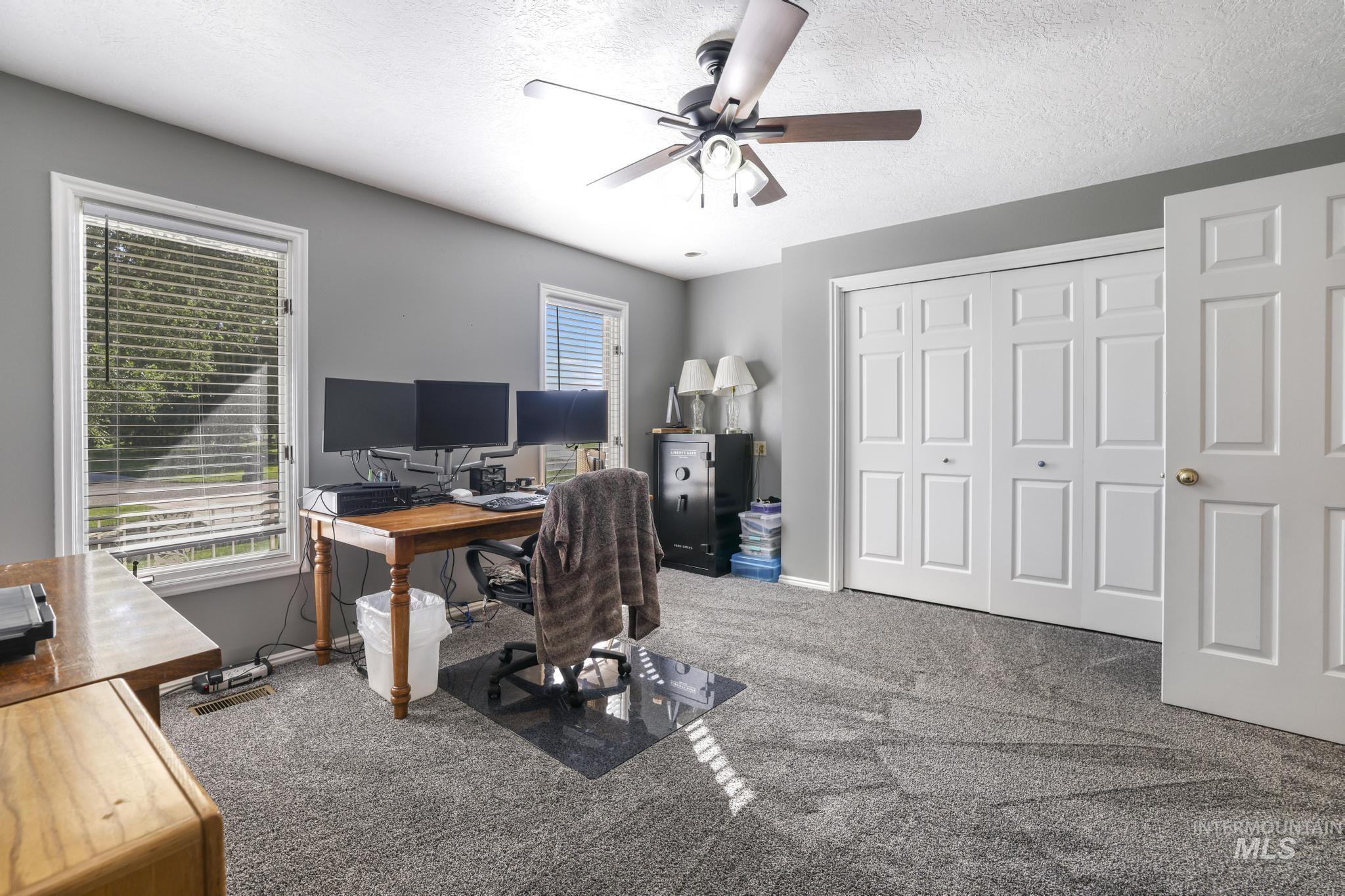 Office with carpet, a textured ceiling, and a ceiling fan