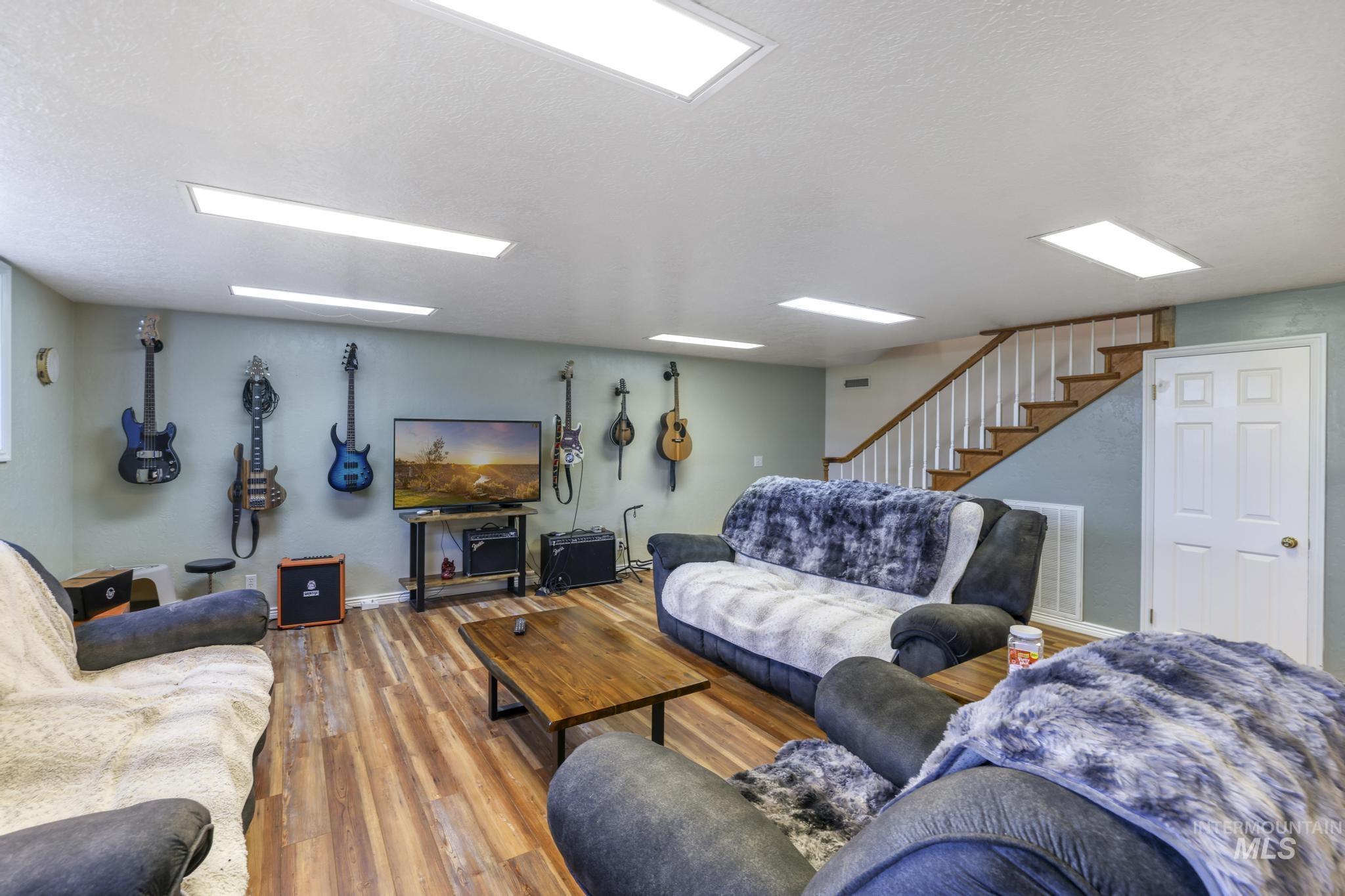 Living room featuring wood finished floors, a textured ceiling, and stairs