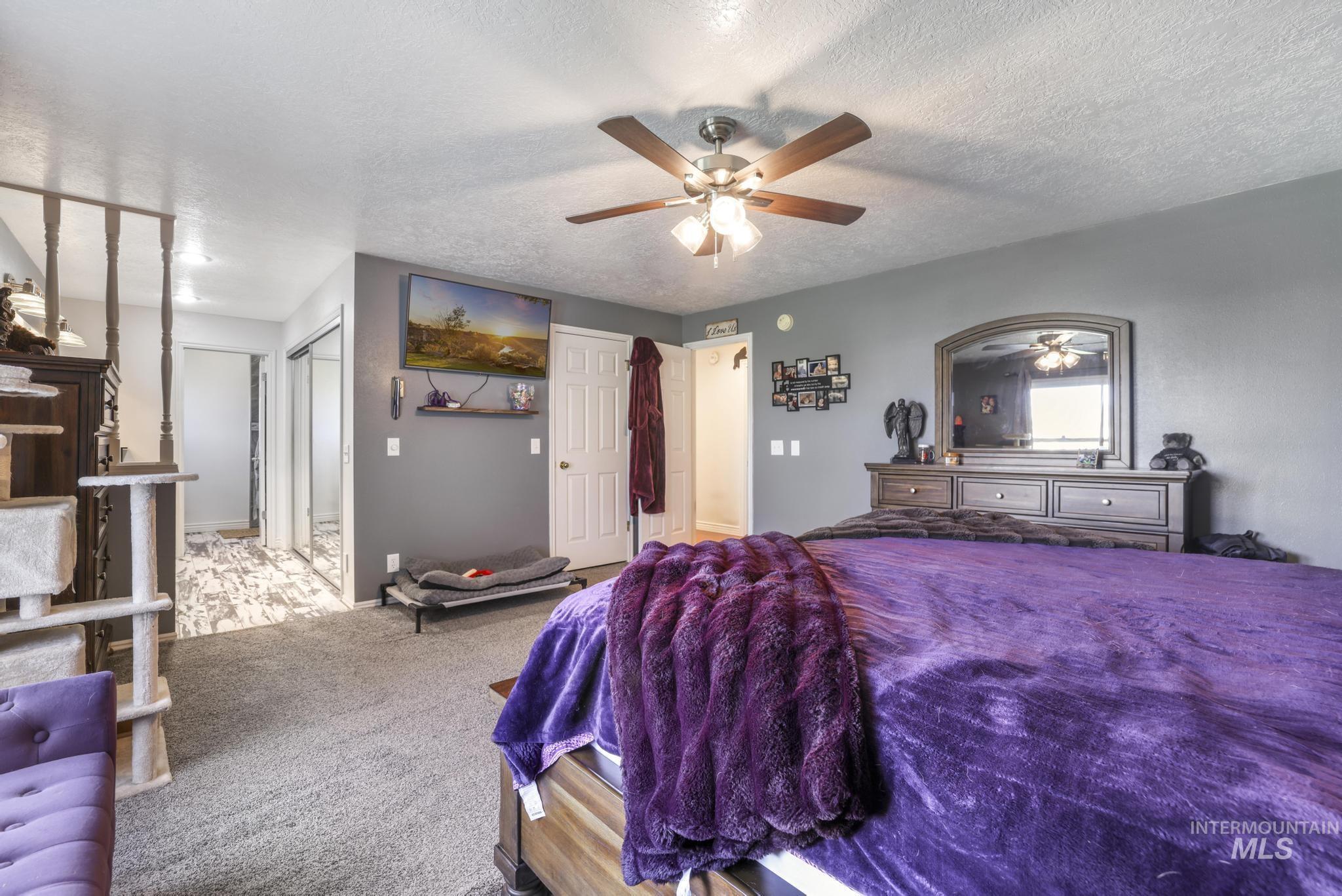 Bedroom with a textured ceiling, carpet floors, a closet, and ceiling fan