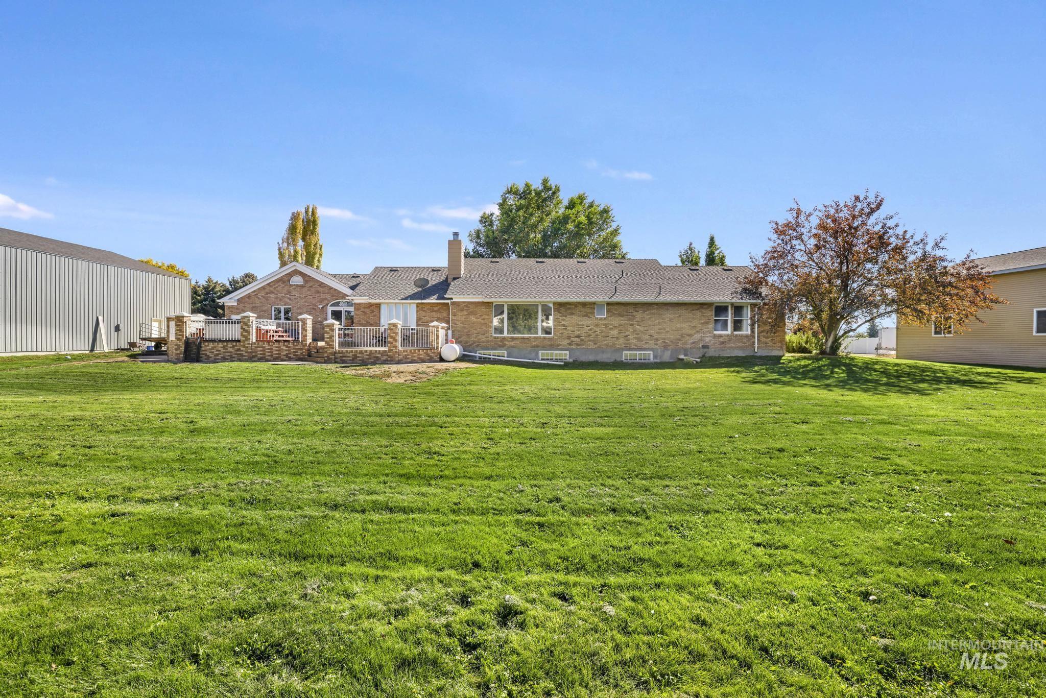 Rear view of property featuring brick siding, a lawn, and a chimney