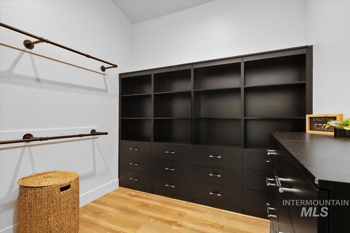 Walk in closet featuring light wood-style flooring and built in storage.