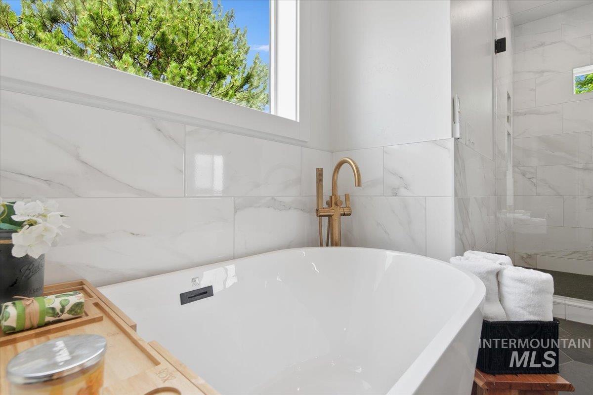 Full bath featuring a freestanding tub and tile walls