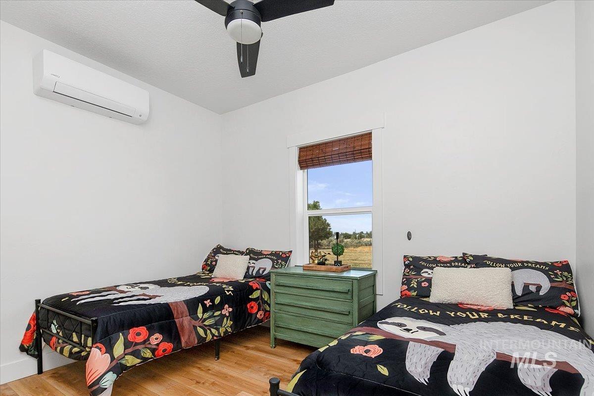 Bedroom featuring light wood-style floors, ductless heating/cooling, and a ceiling fan