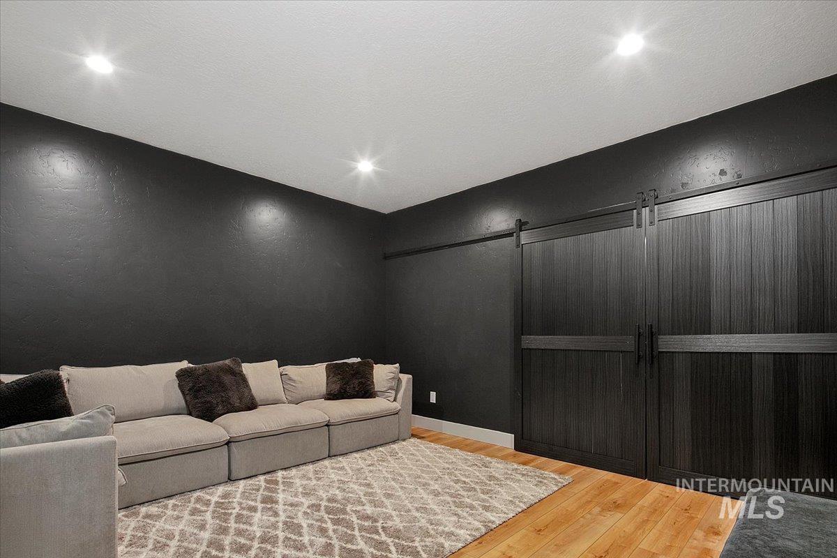 Home theater with wood finished floors, a barn door, and recessed lighting, or 5th bedroom