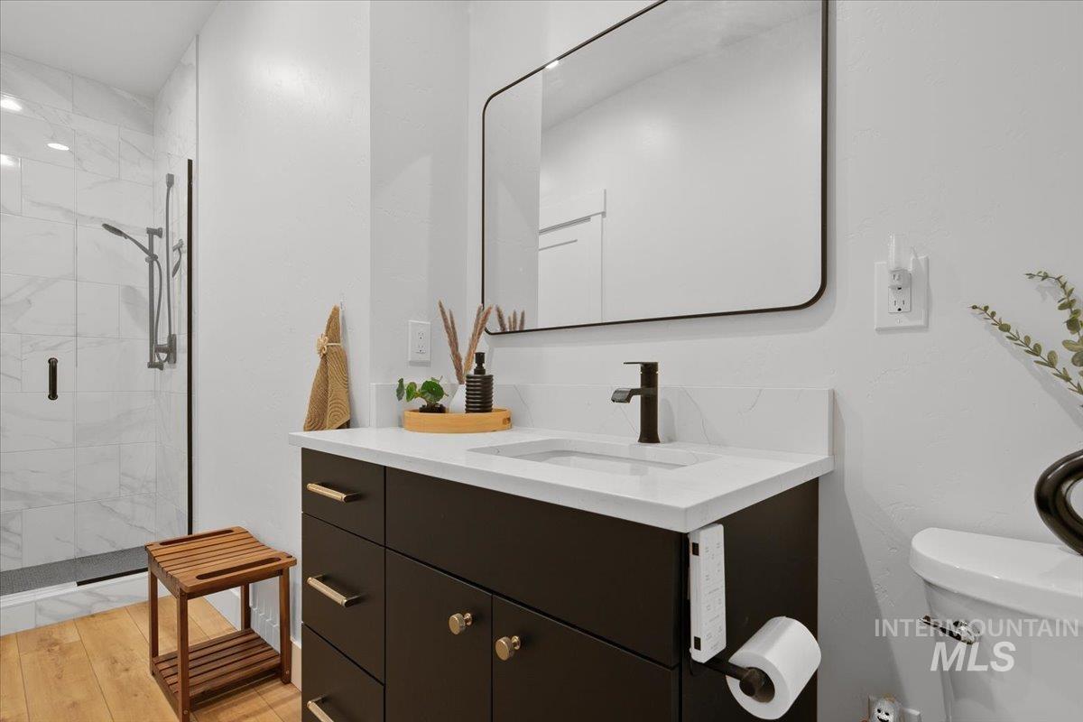 Full bathroom featuring a shower stall, vanity, and wood finished floors