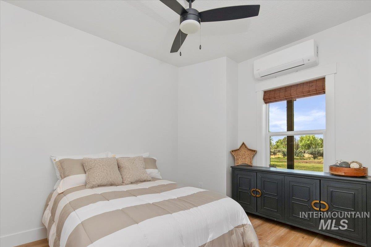 Bedroom featuring light wood-style floors, ductless heating/cooling, and a ceiling fan