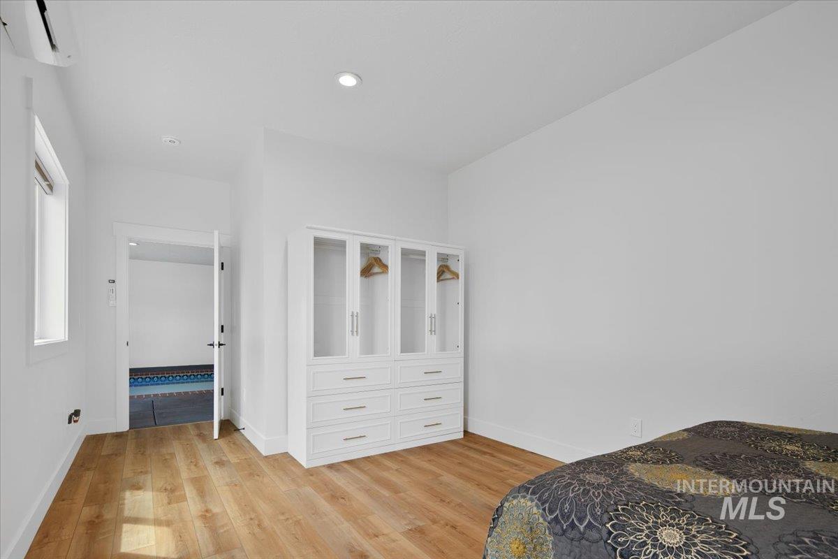 Bedroom with light wood finished floors, ductless heating/cooling and recessed lighting