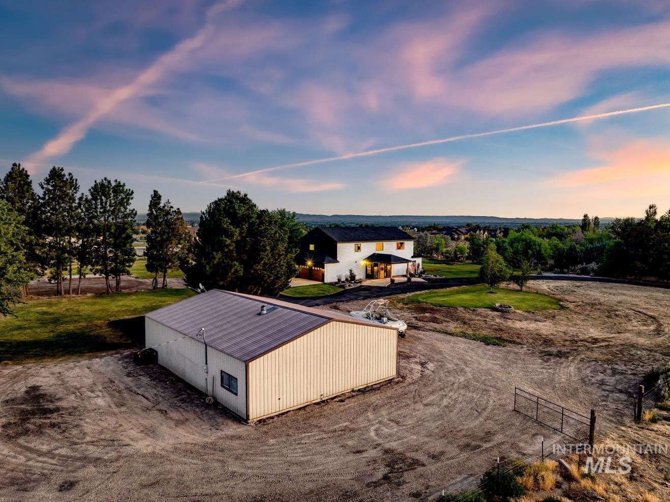 Aerial view at dusk of the shop & rv parking area of property as well as front pasture.