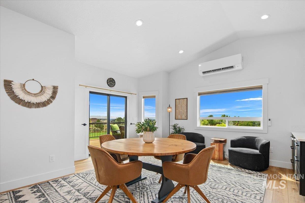 Dining area featuring vaulted ceiling, healthy amount of natural light, light wood-style flooring, a ductless splitter, and recessed lighting