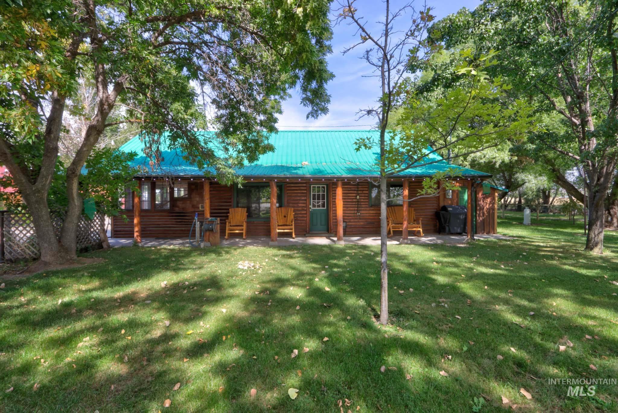 Rear view of house featuring a yard, faux log siding, a metal roof, and a patio