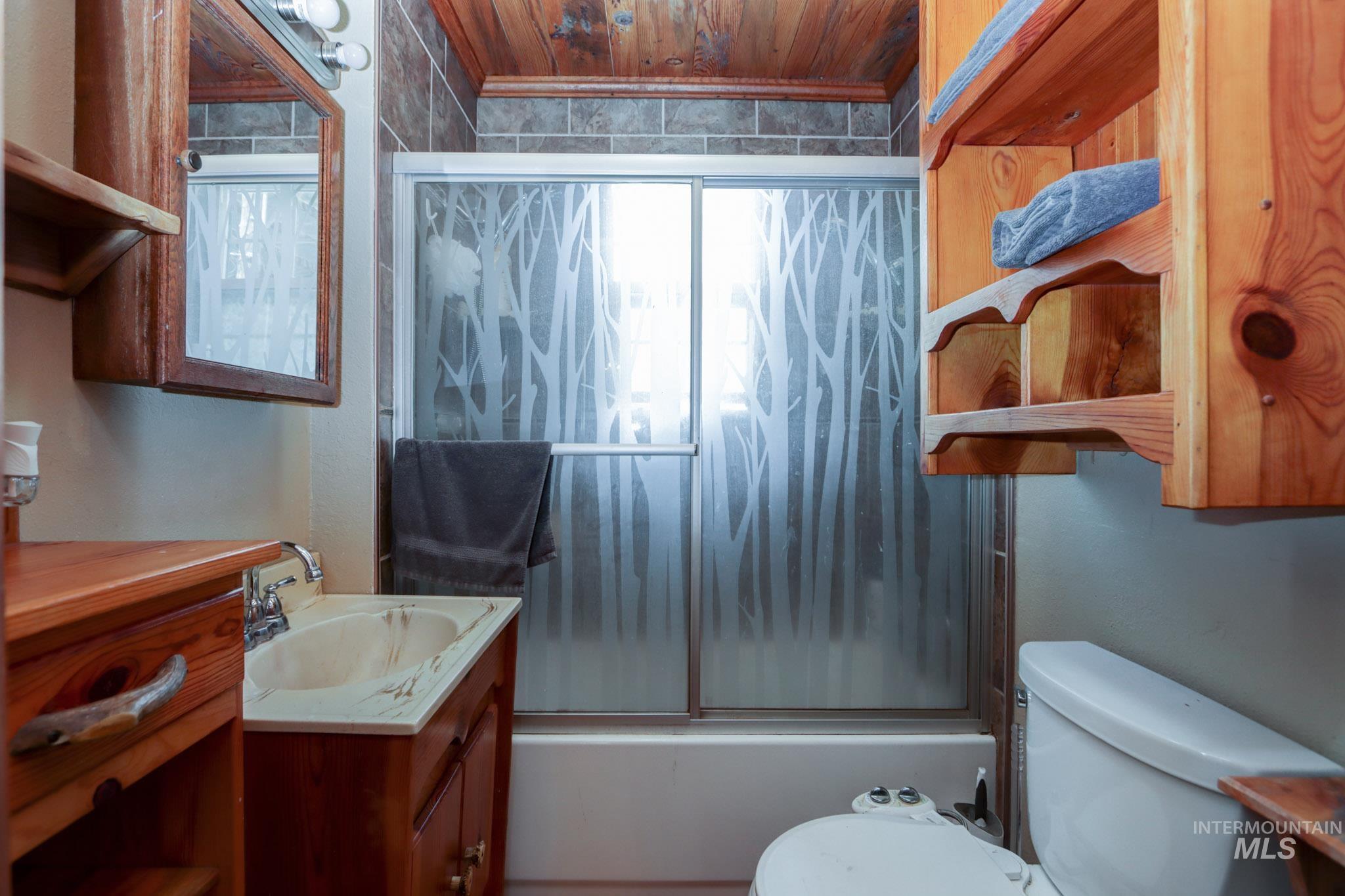 Bathroom with vanity, enclosed tub / shower combo, and wooden ceiling