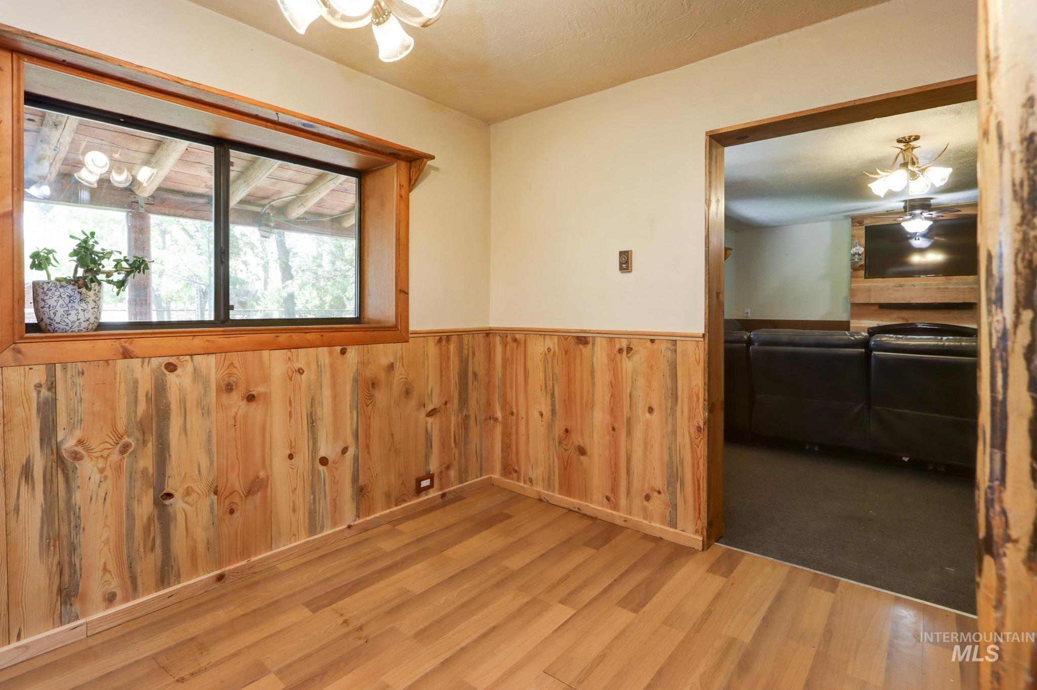 Unfurnished room with wooden walls, a wainscoted wall, wood finished floors, and a chandelier