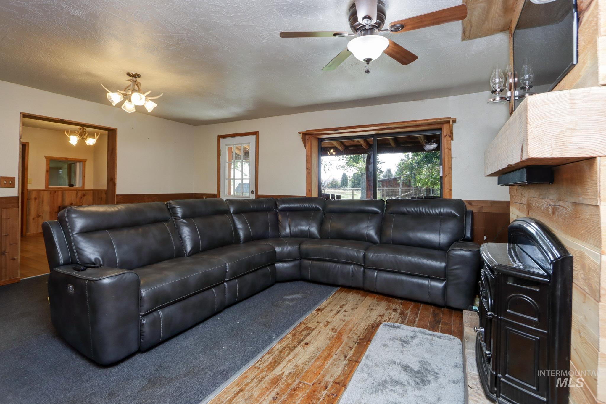 Living area with a wainscoted wall, wooden walls, hardwood / wood-style flooring, a chandelier, and ceiling fan