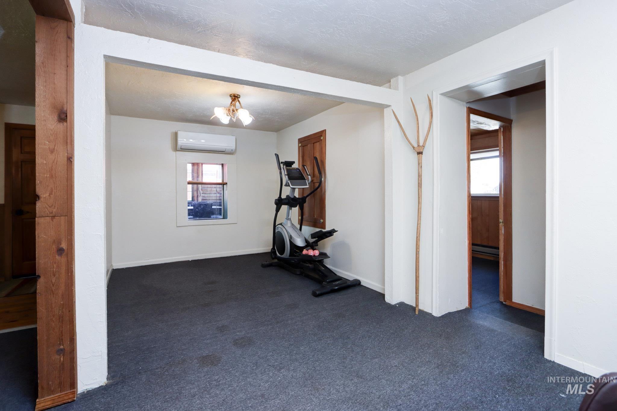Exercise area with healthy amount of natural light, dark carpet, and a baseboard radiator