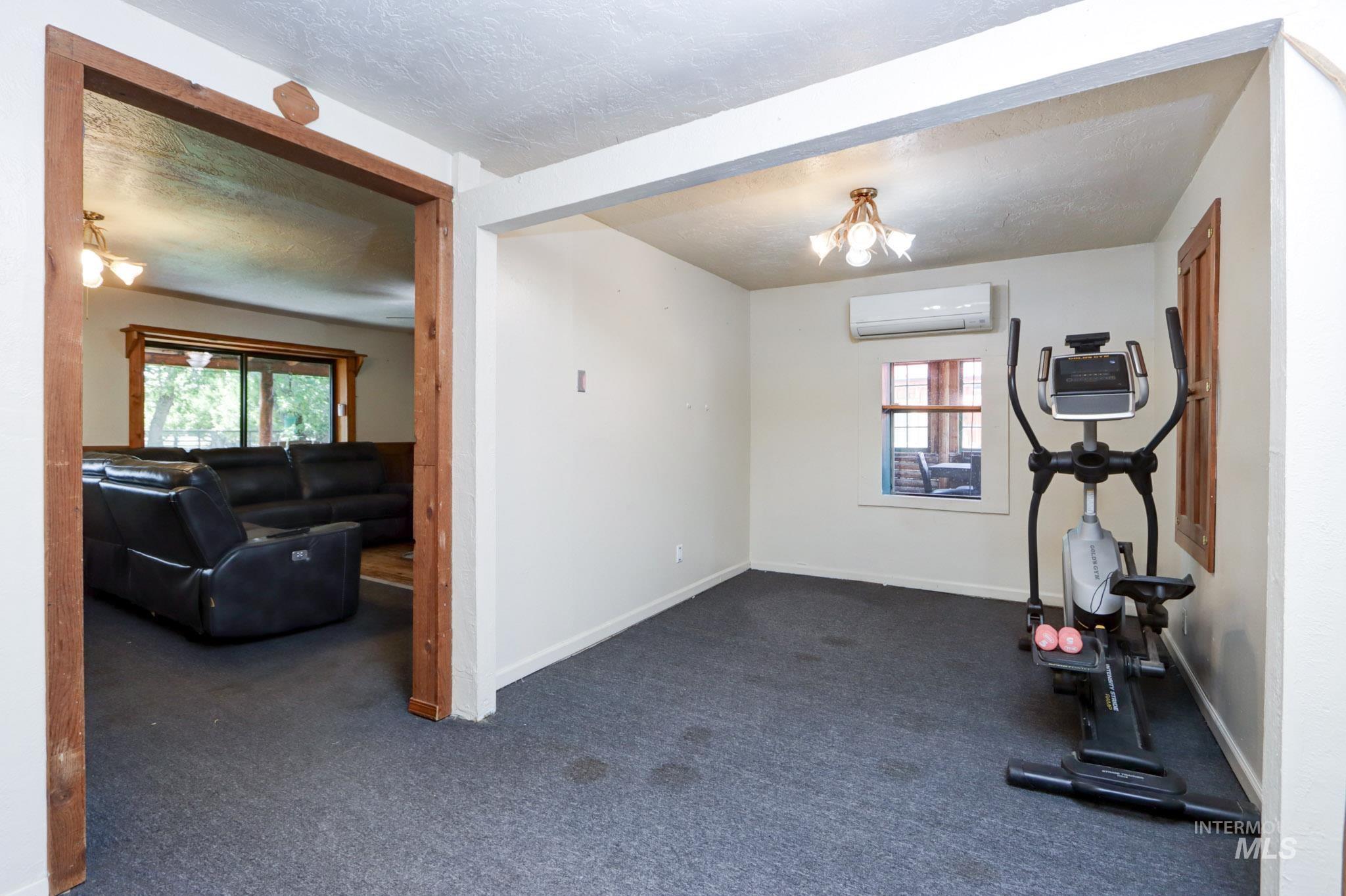 Workout room featuring dark colored carpet, a chandelier, and a textured ceiling