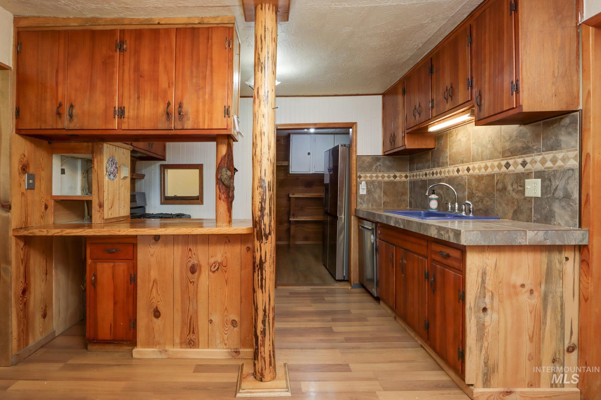 Kitchen featuring brown cabinetry, light wood-style floors, light countertops, appliances with stainless steel finishes, and a textured ceiling
