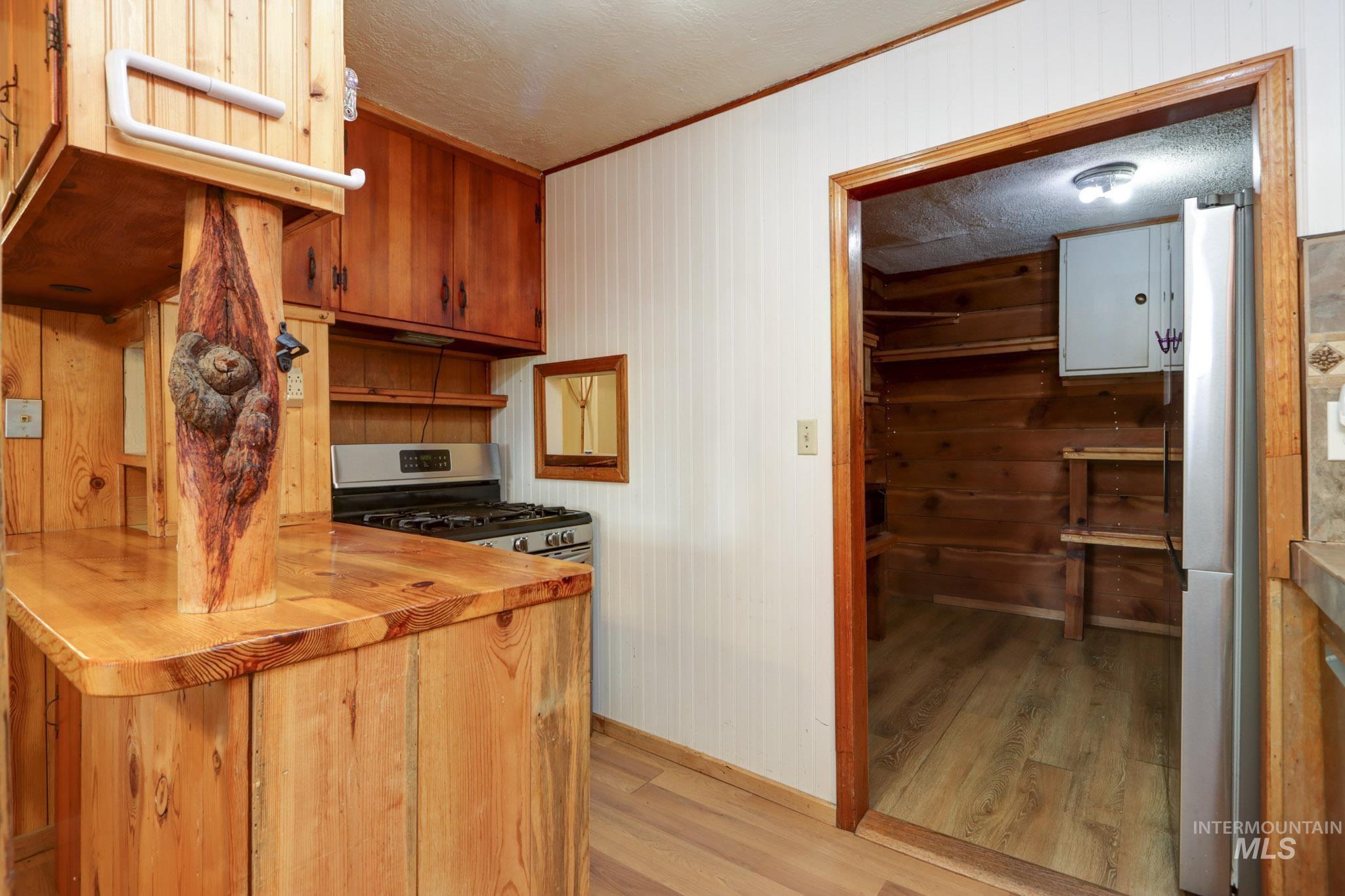 Kitchen with light wood-style floors, butcher block counters, wooden walls, brown cabinets, and crown molding