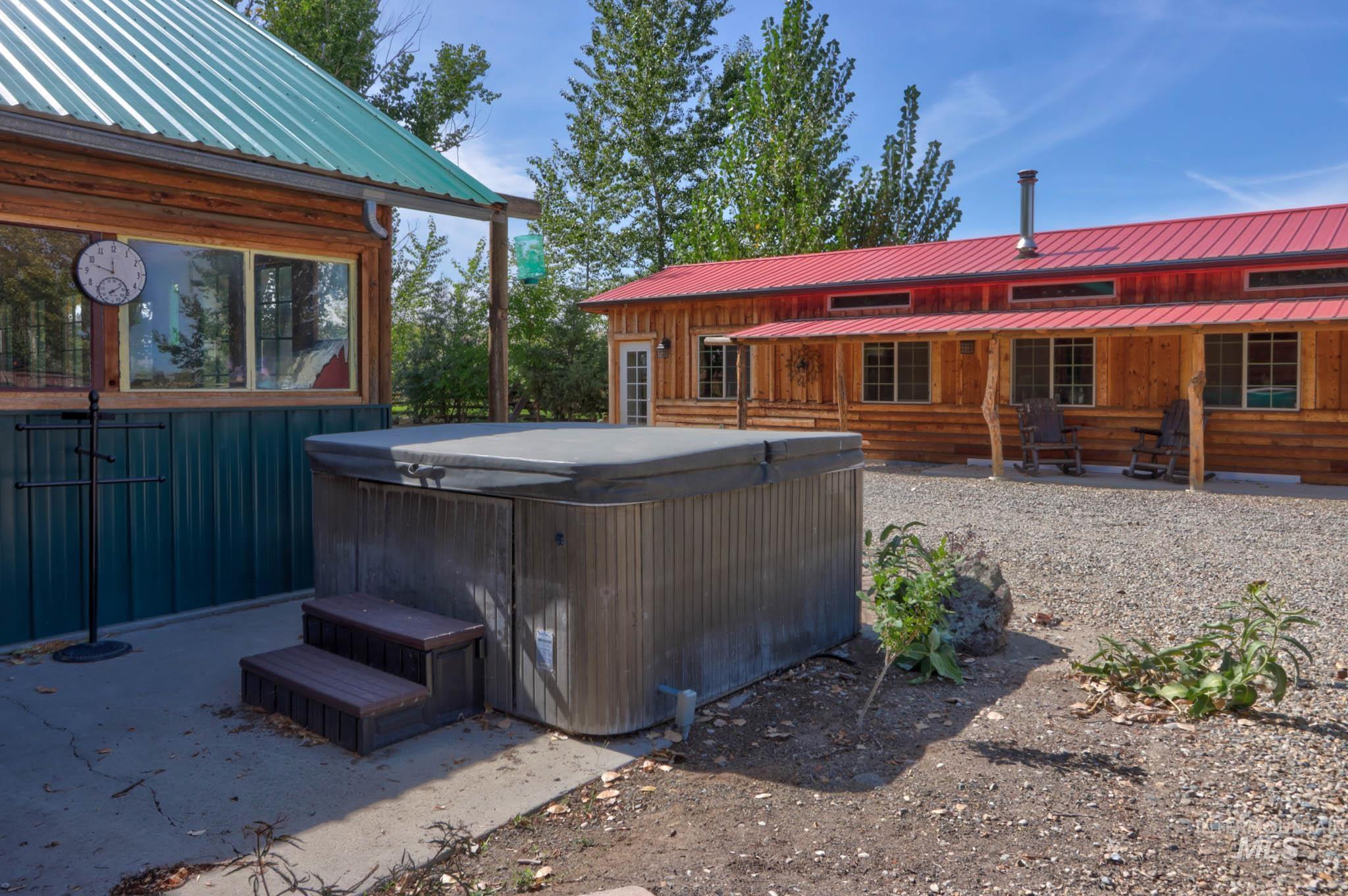 Back of house featuring a hot tub, a metal roof, a patio, and board and batten siding