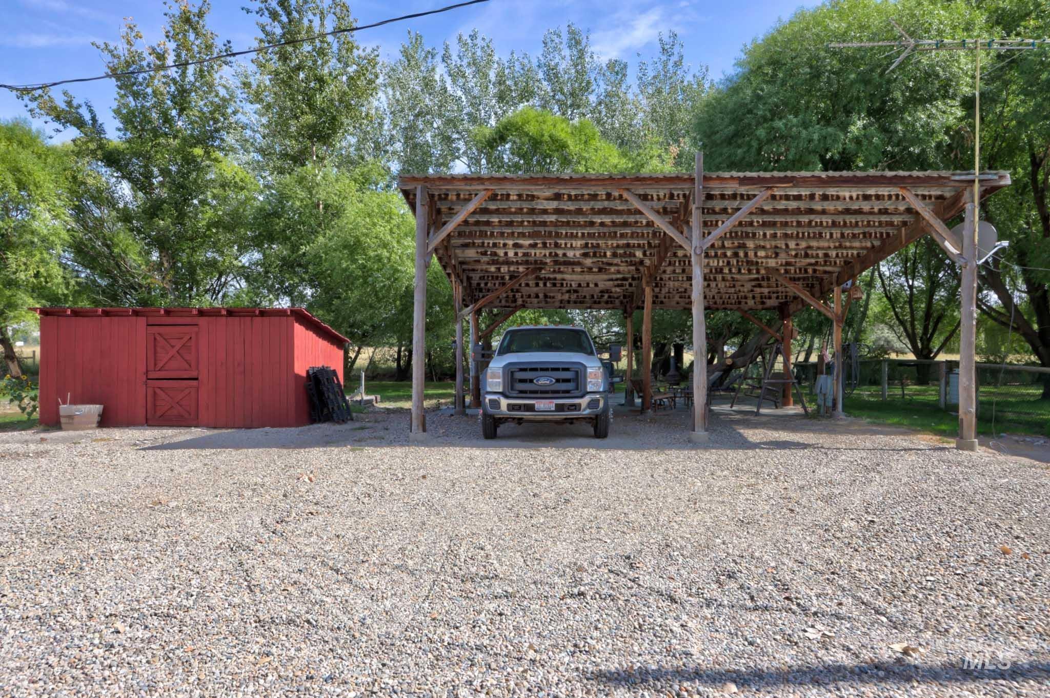 View of parking / parking lot featuring a carport and gravel driveway