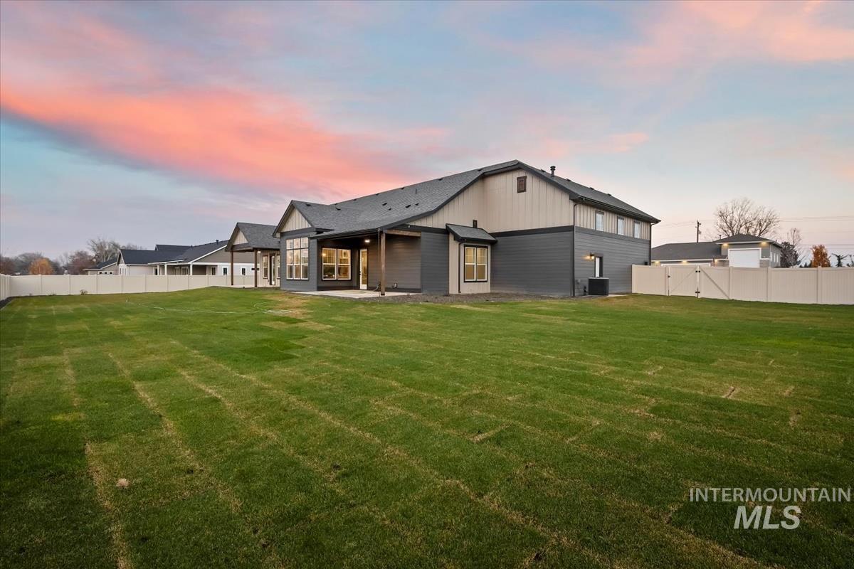 Back of property at dusk featuring a fenced backyard and a patio