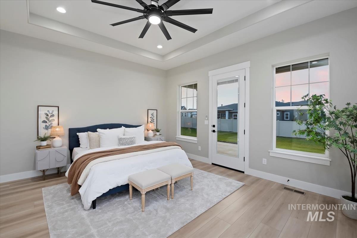 Bedroom featuring a raised ceiling, light wood finished floors, access to outside, ceiling fan, and recessed lighting