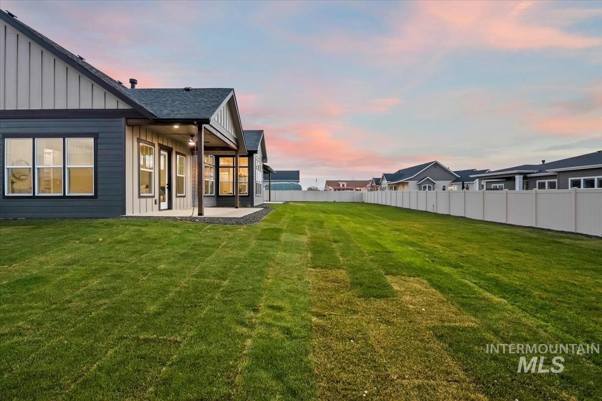 Yard at dusk with a fenced backyard and a patio area