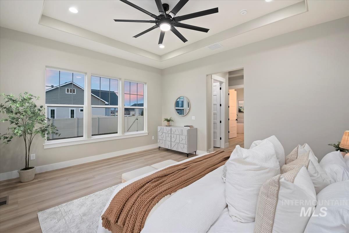 Bedroom with a tray ceiling, ceiling fan, wood finished floors, and recessed lighting