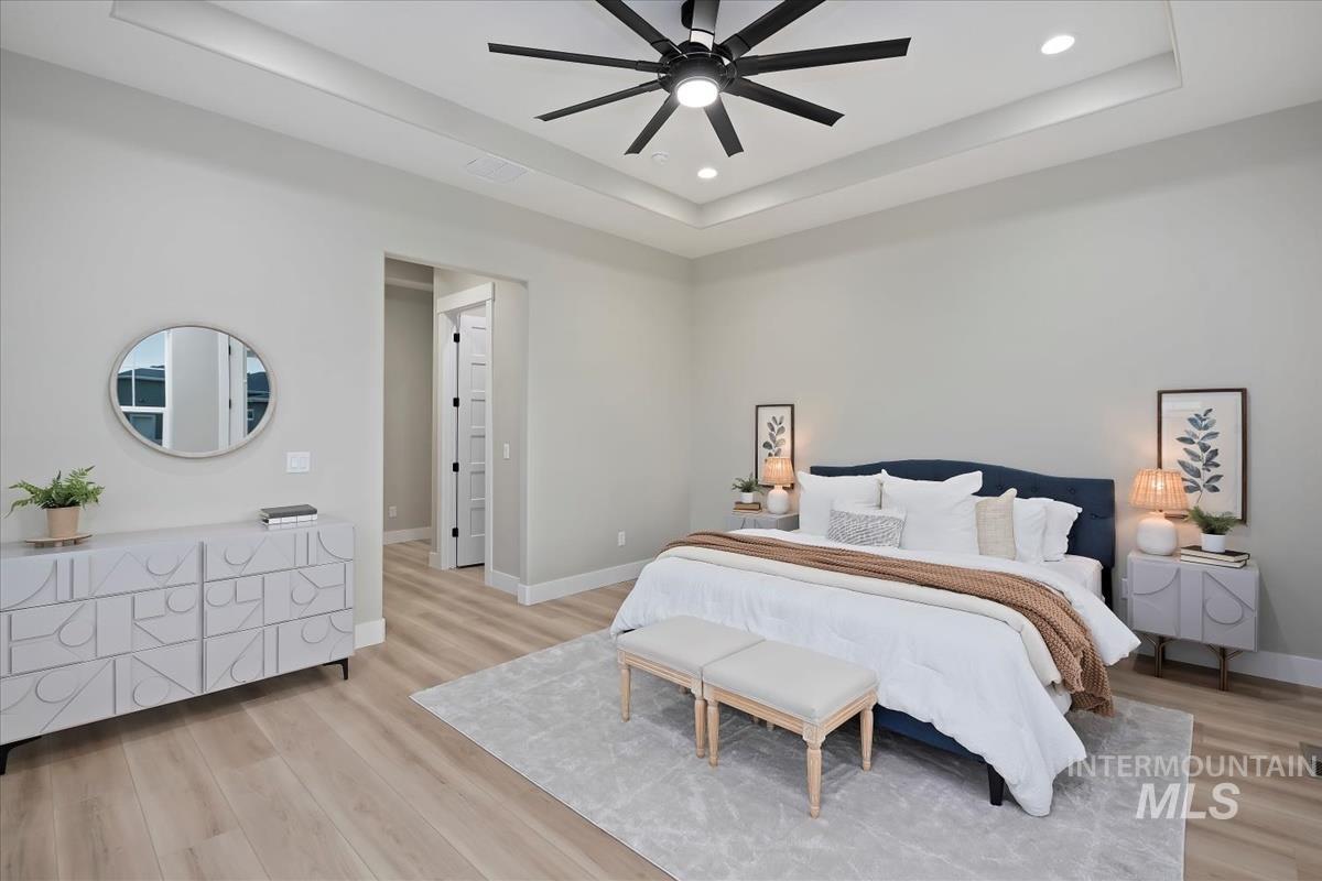 Bedroom featuring a raised ceiling, light wood finished floors, ceiling fan, and recessed lighting