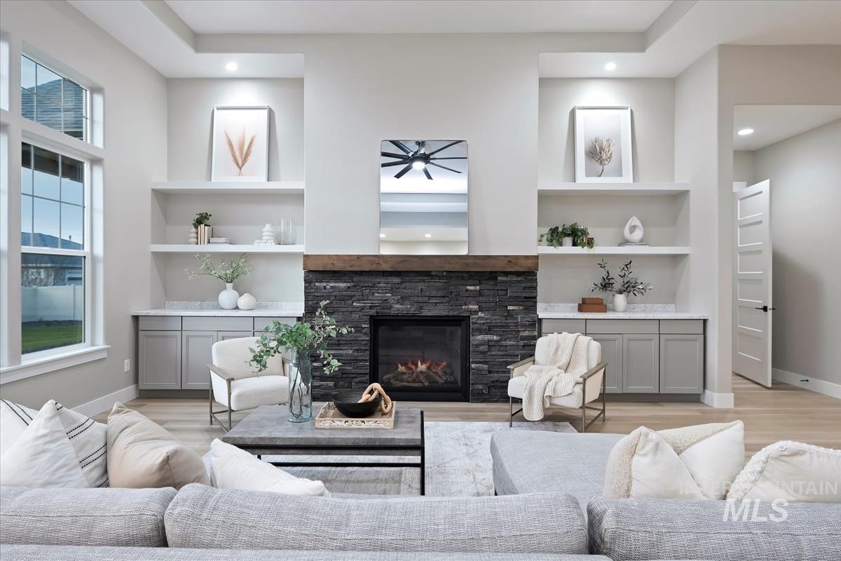 Living area with built in features, a fireplace, light wood-style flooring, and recessed lighting