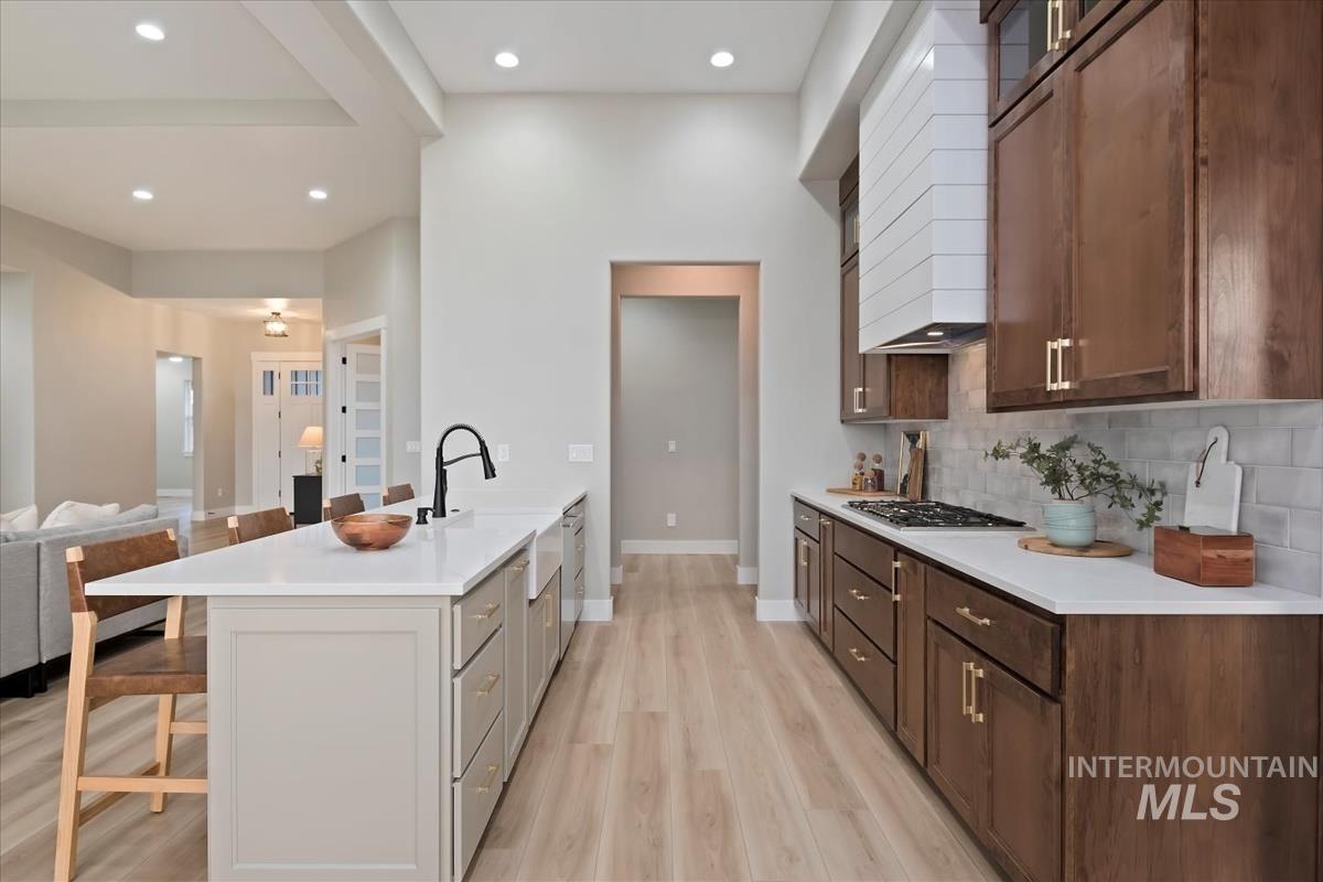 Kitchen with a kitchen breakfast bar, a peninsula, open floor plan, custom exhaust hood, and recessed lighting