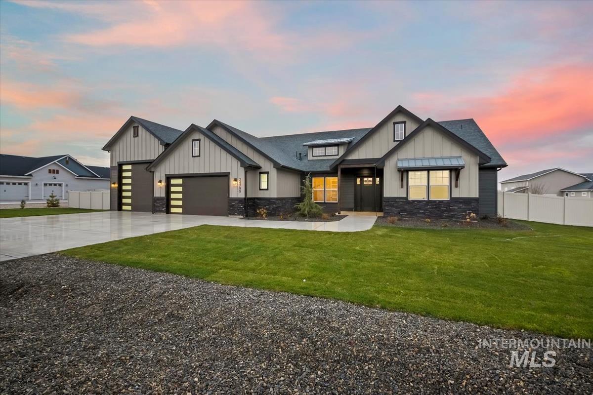 View of front of property featuring stone siding, board and batten siding, concrete driveway, an attached garage, and a shingled roof