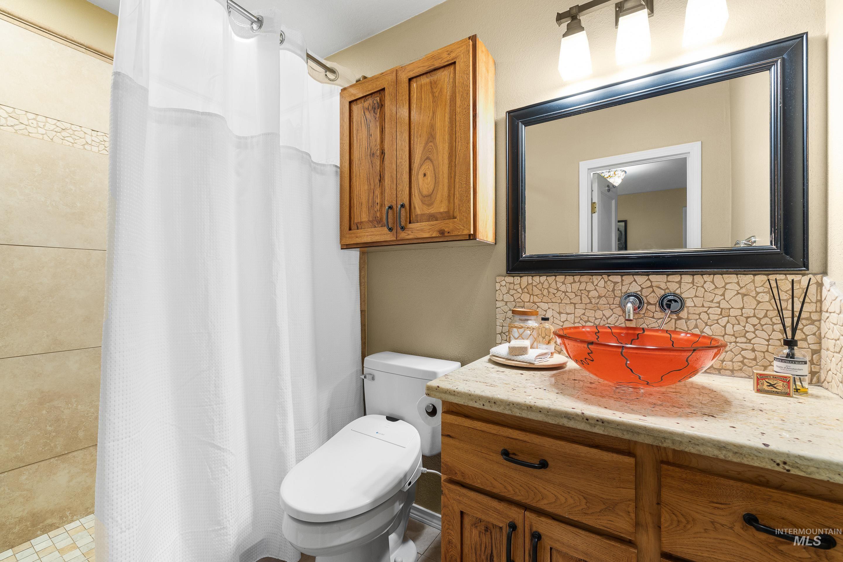 Bathroom featuring backsplash, a stall shower, and vanity