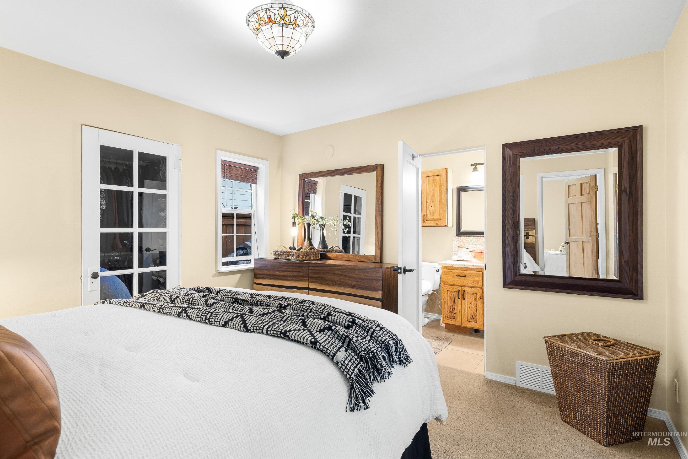 Bedroom featuring light colored carpet and ensuite bathroom