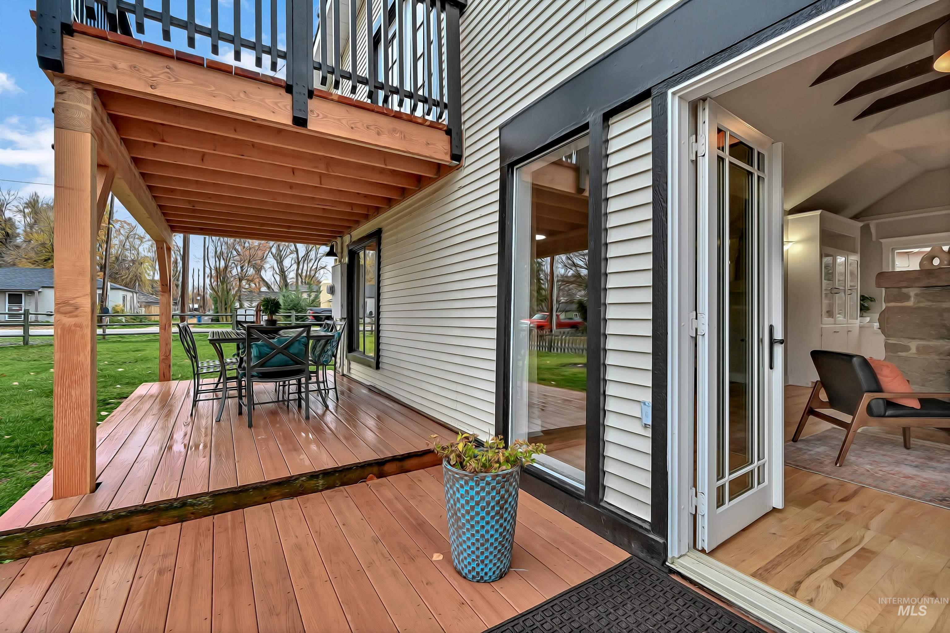 Inviting indoor?outdoor flow with French doors opening to a spacious deck. Covered dining area below the upper balcony offers a great spot for entertaining. Warm natural light and clean finishes visible inside.