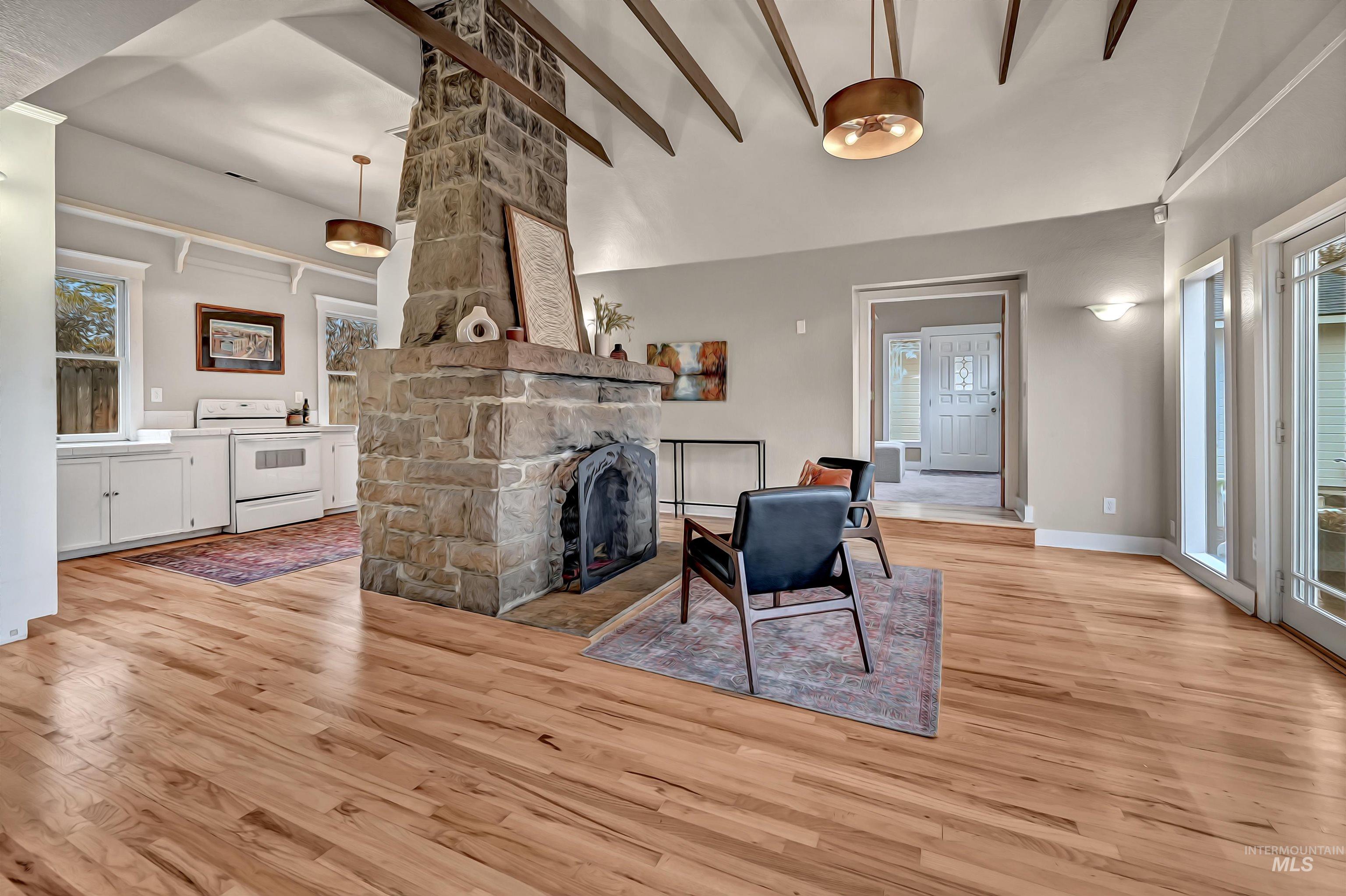 Warm hardwood floors, exposed beams, and modern light fixtures complement the central stone fireplace and open layout.